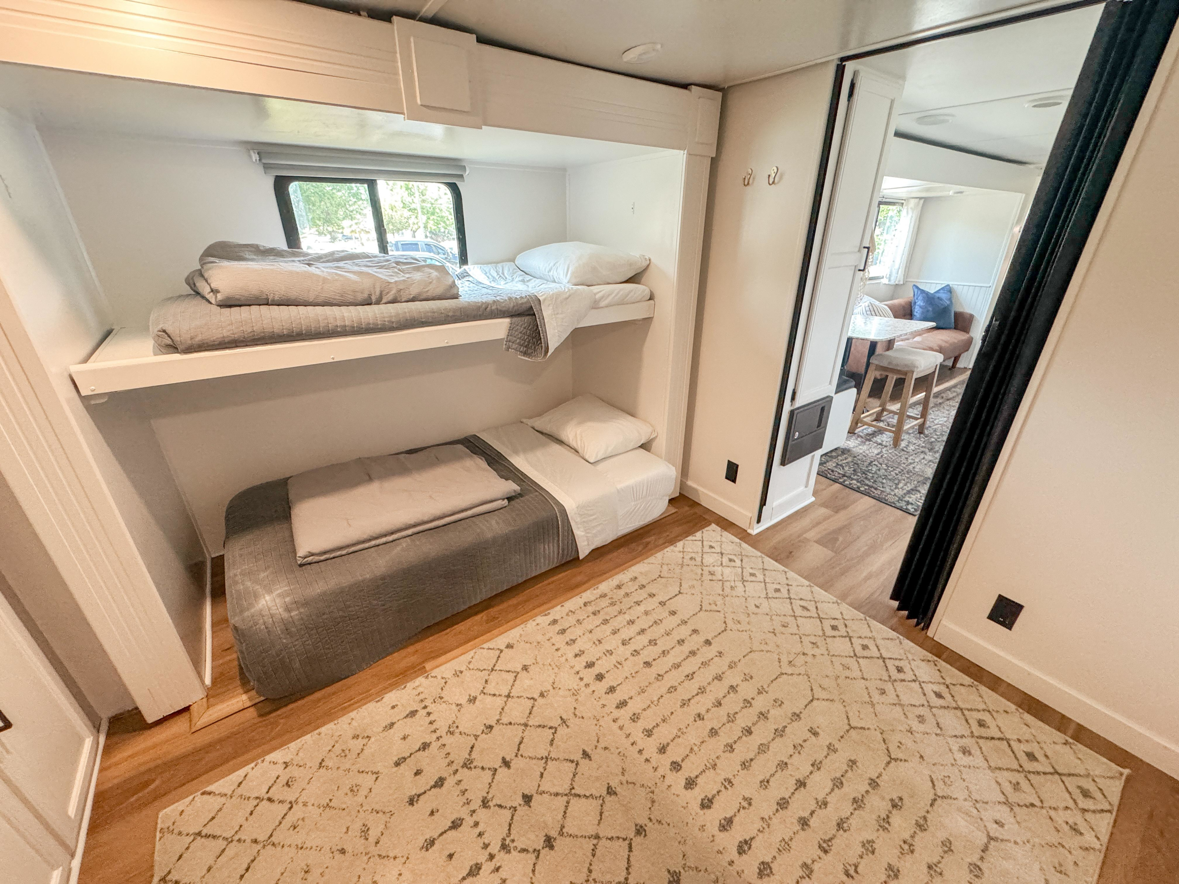 Cozy RV rental features modern bunk beds and a view to the living area, ideal for family travel.. Keystone Passport 2017