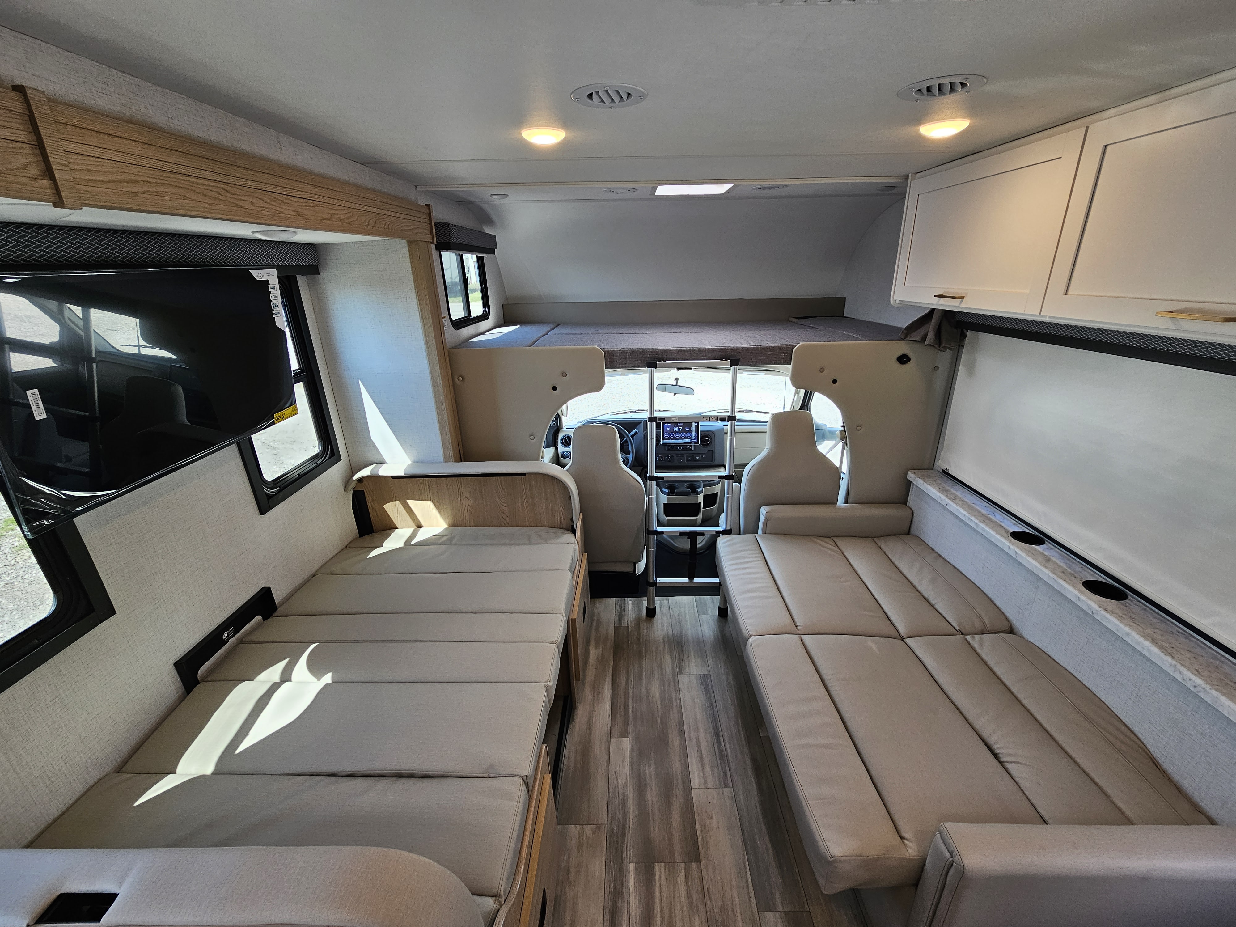Spacious RV rental interior: View of modern living space with multiple sleeping areas, including an over-cab bunk and convertible sofas.. Thor Motor Coach Four Winds 2026