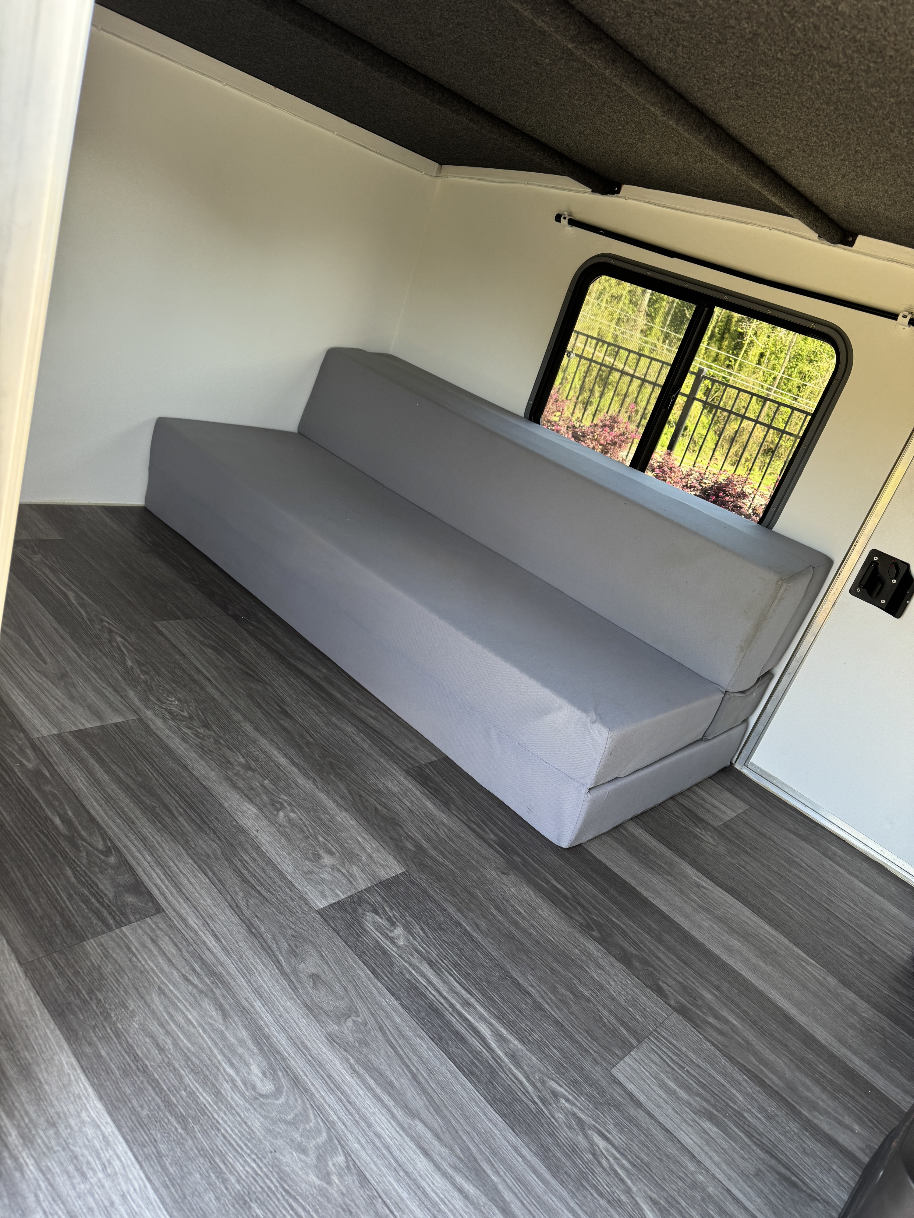Experience comfort in this RV rental with a gray sofa bed, stylish wood-look floor, and bright window.. Runaway Campers RangeRunner 2018