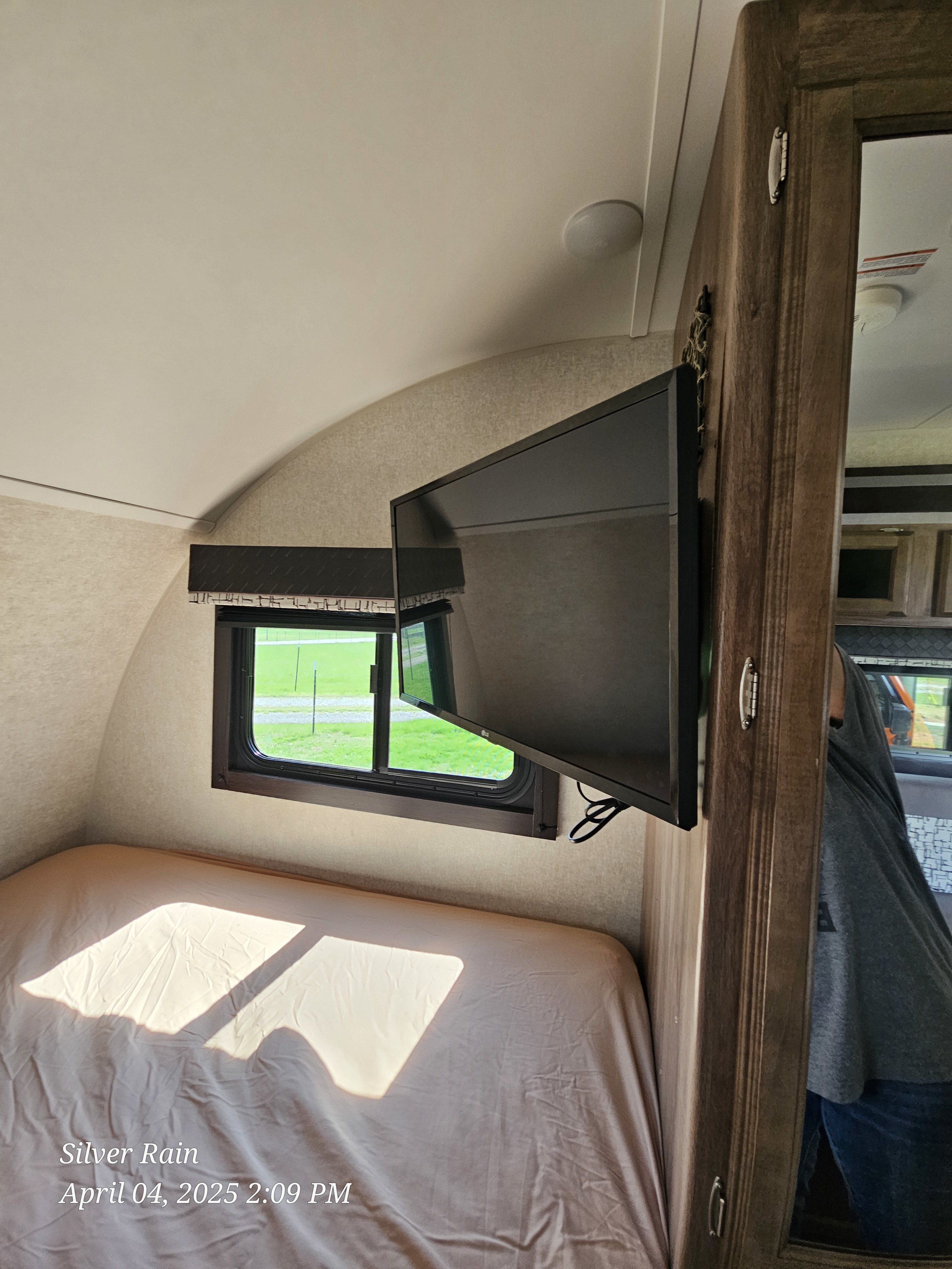 Cozy RV rental interior with a bed, window view, and TV.. Jayco Hummingbird 2020