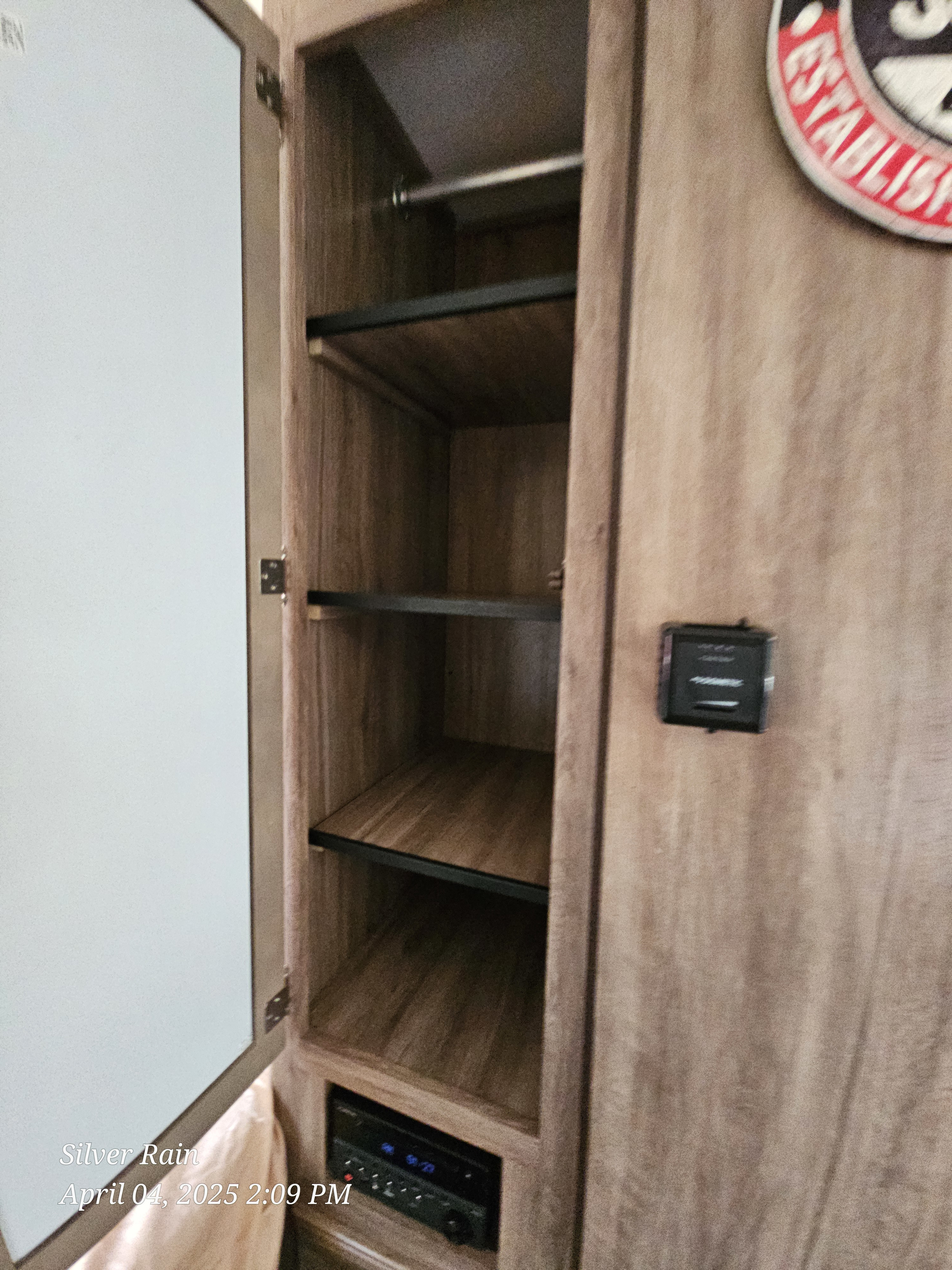 Open cabinet in an RV rental, featuring shelves, a hanging rod, and an entertainment unit for organized storage.. Jayco Hummingbird 2020