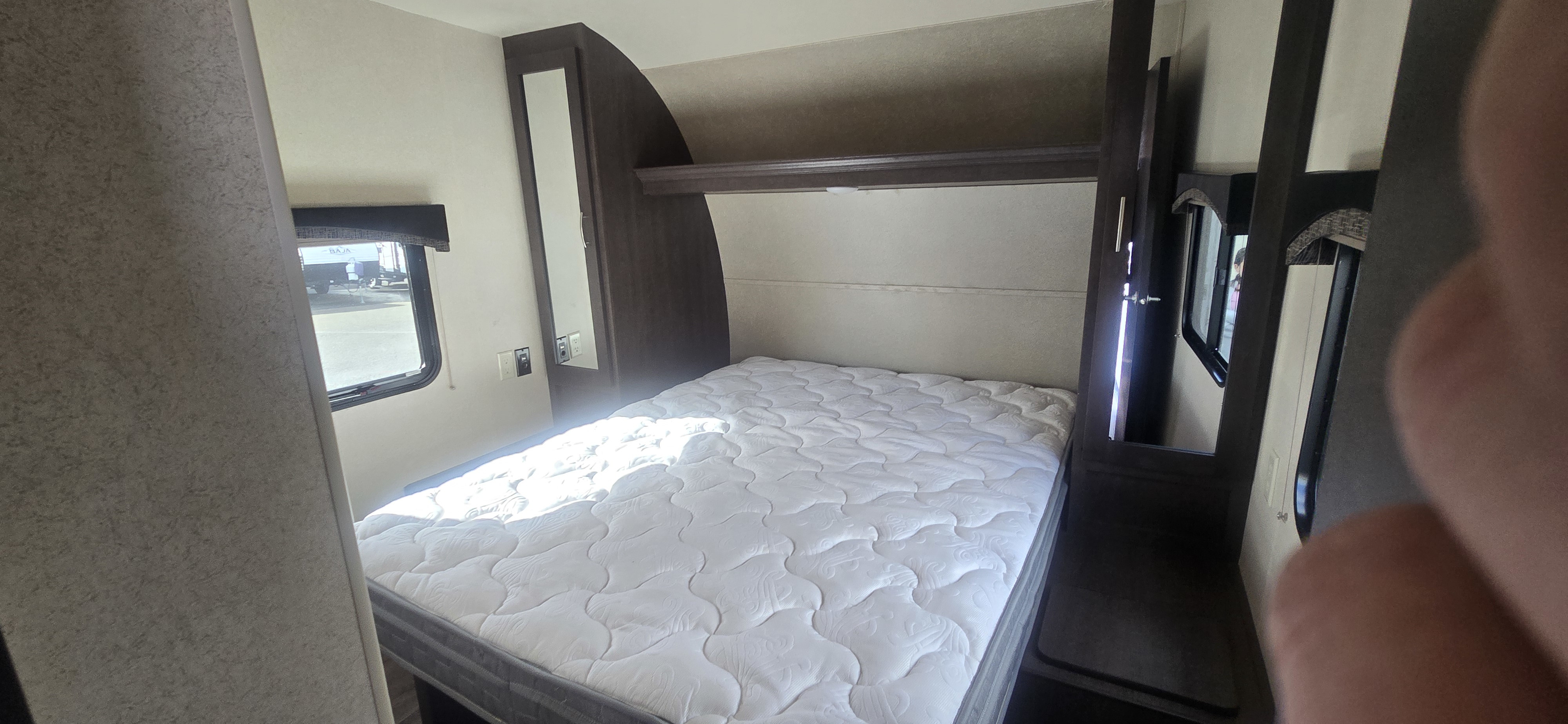 Cozy RV rental bedroom with white mattress, compact storage, and bright window view, perfect for travel.. Forest River Shockwave 2018