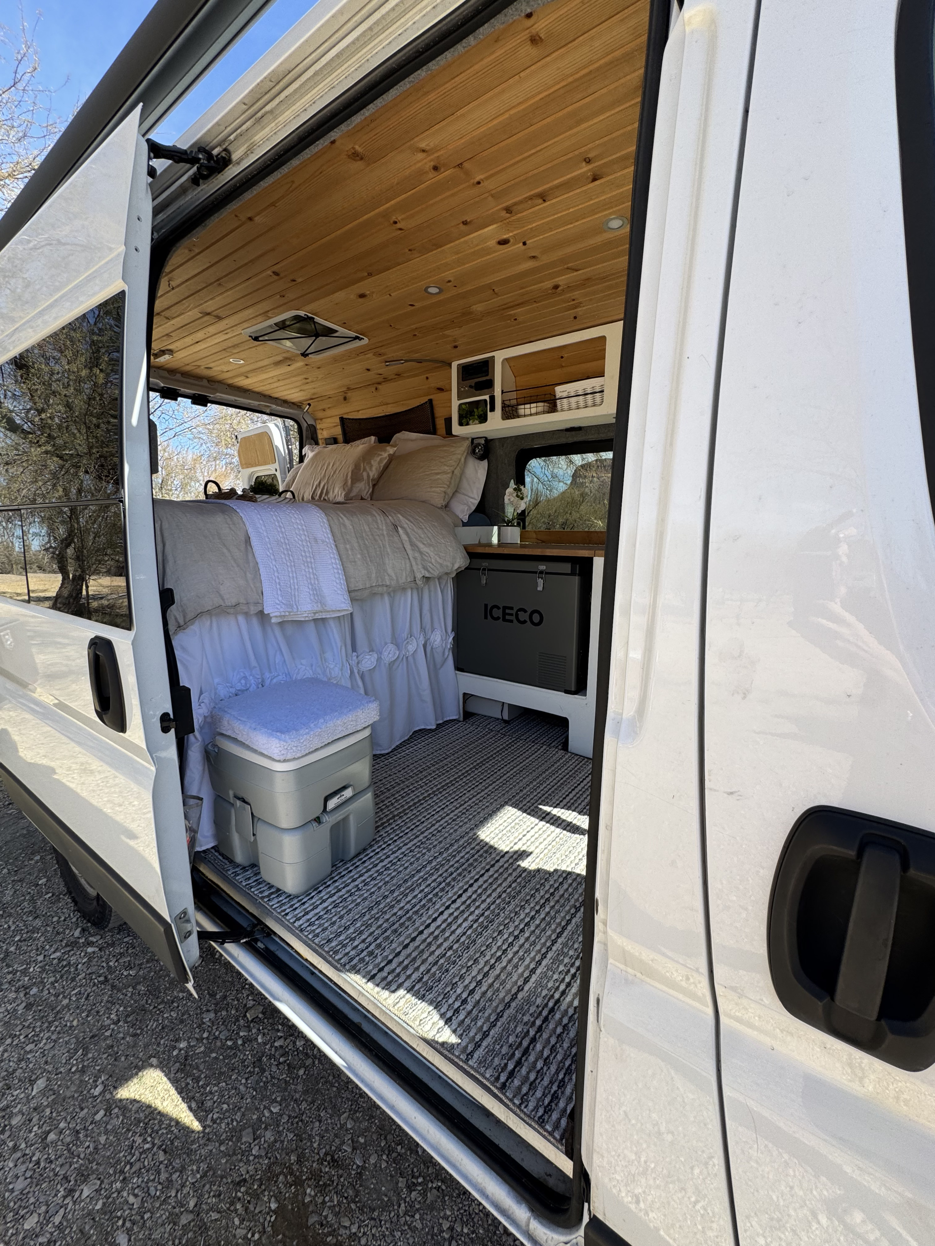 RV rental interior: cozy bed, ICECO fridge, portable toilet, and wood-paneled ceiling. Ready for your adventure.. Dodge Ram 1500 2019