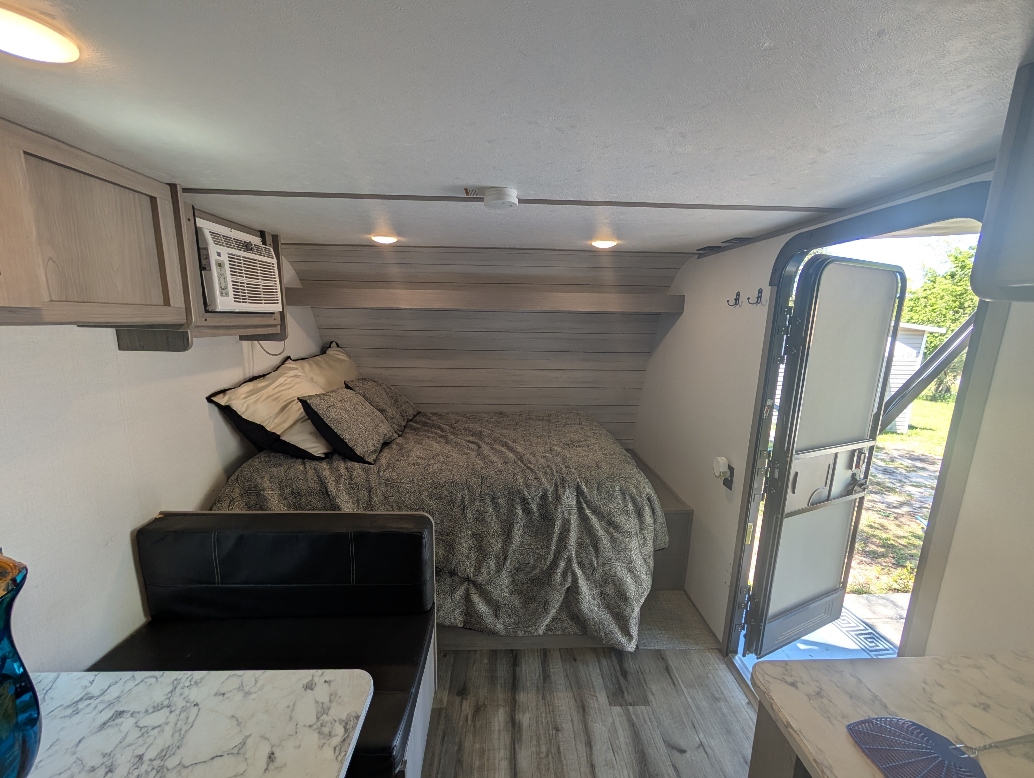 Step inside this cozy RV rental: compact bedroom with AC, dinette, and open door to nature.. Keystone RV Coleman Lantern 17b 2024