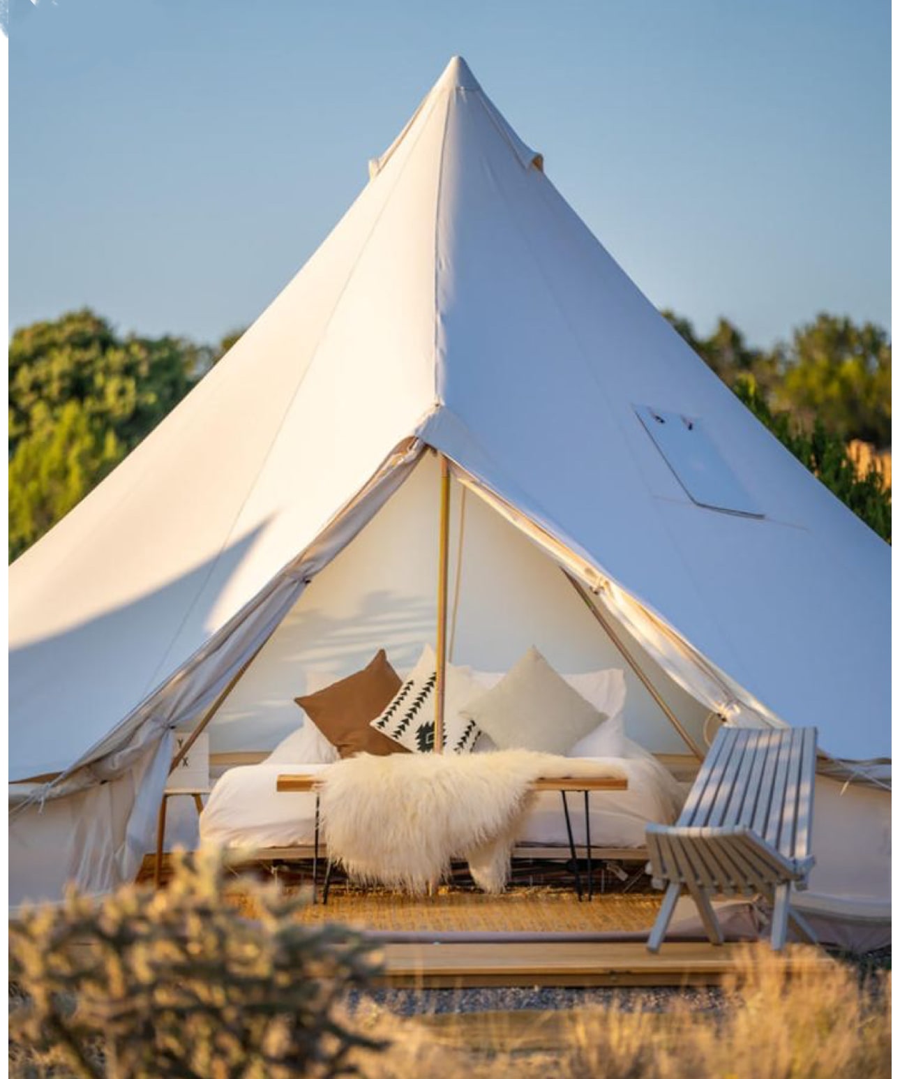 Beyond RV rental: luxurious glamping in a spacious bell tent with a comfy bed and outdoor lounge chair.. Keystone RV Springdale 2019