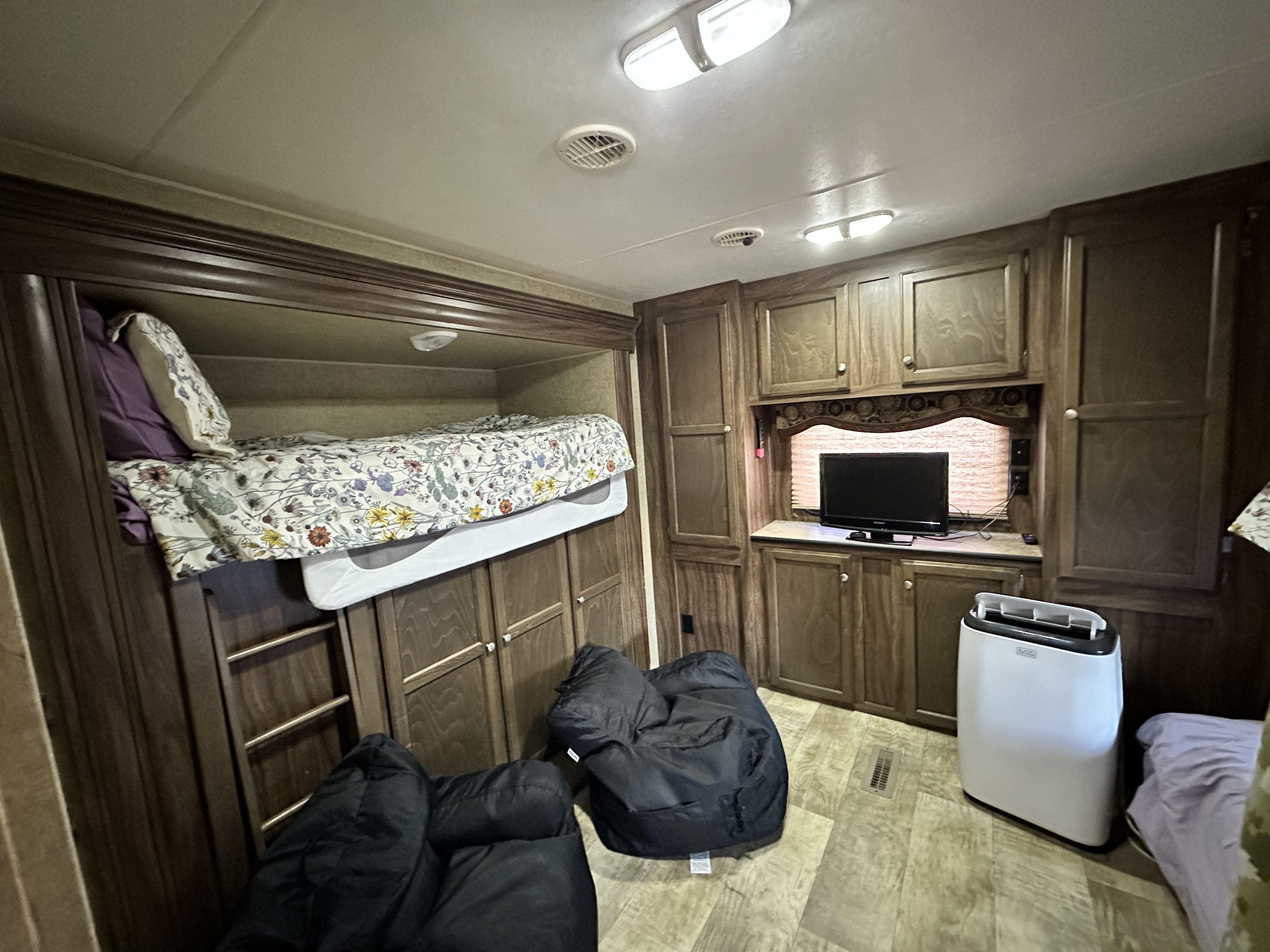 Inside this RV rental: bunk beds with a ladder, bean bag chairs, a TV entertainment unit, and a portable AC for a compact living space.. KZ RV Sportsmen 2016