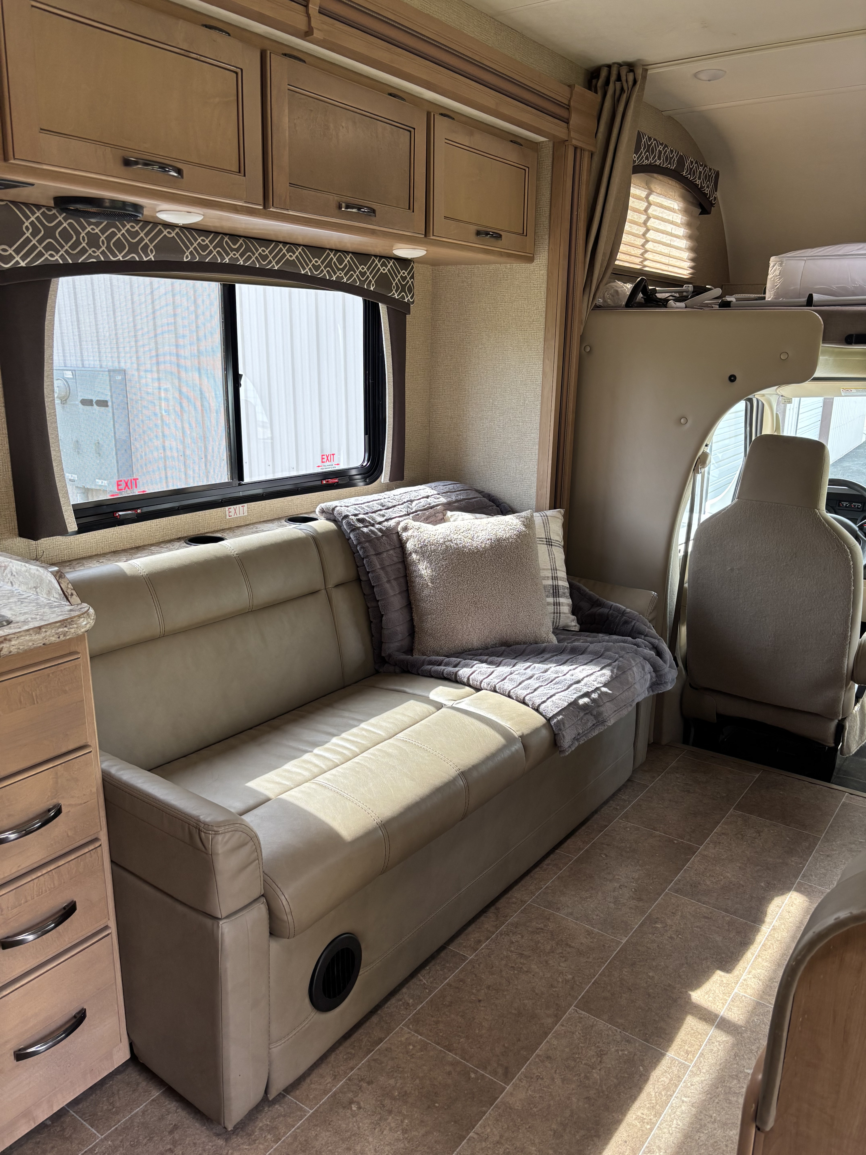 Step inside this inviting RV rental. Features a spacious living area with a comfortable sofa, overhead cabinets, and large window.. Thor Chateau 2019