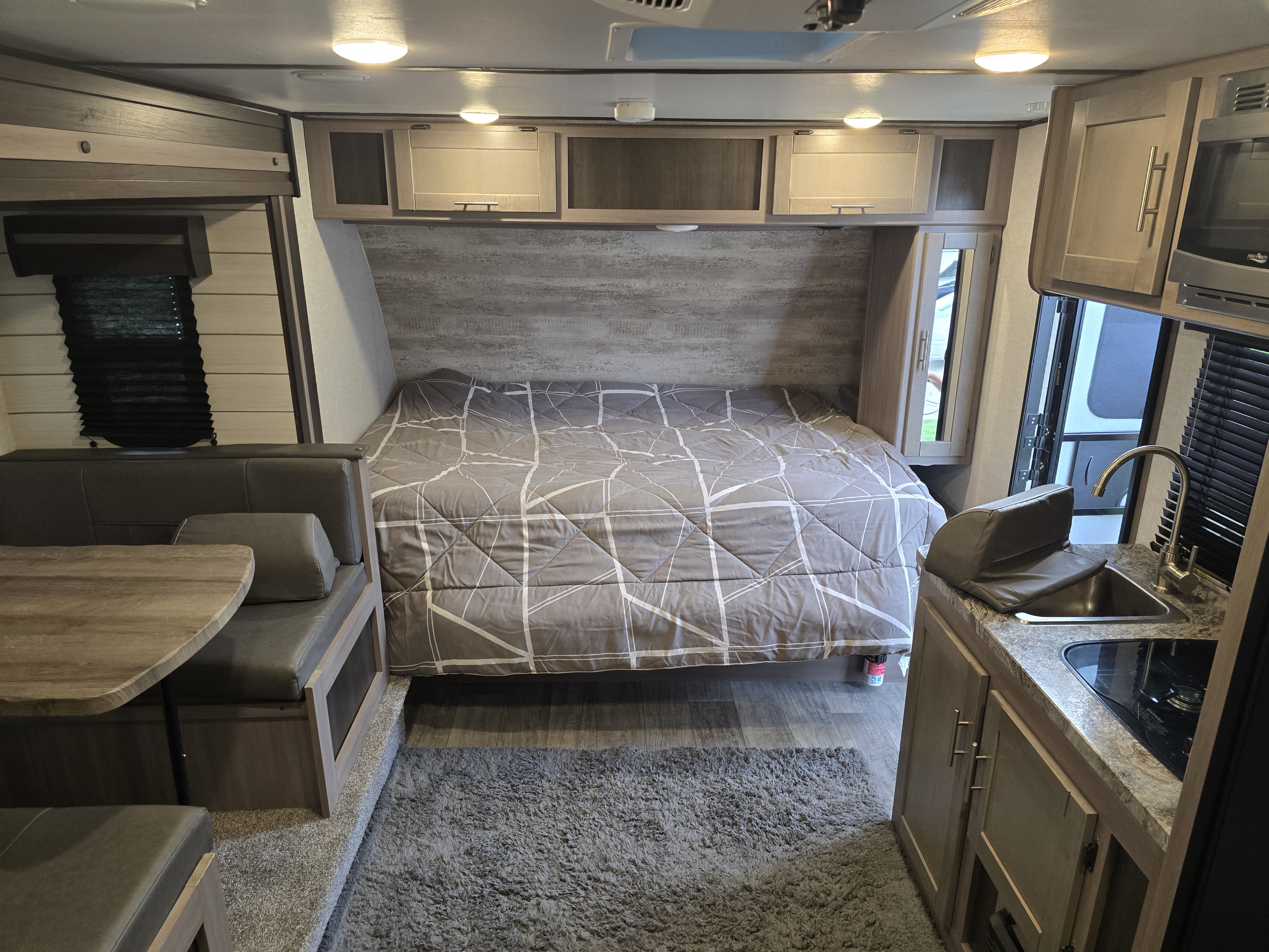 Cozy RV rental interior showcasing a comfy bed, dinette, and functional kitchen with modern finishes.. Crossroads RV Sunset Trail Super Lite 2021