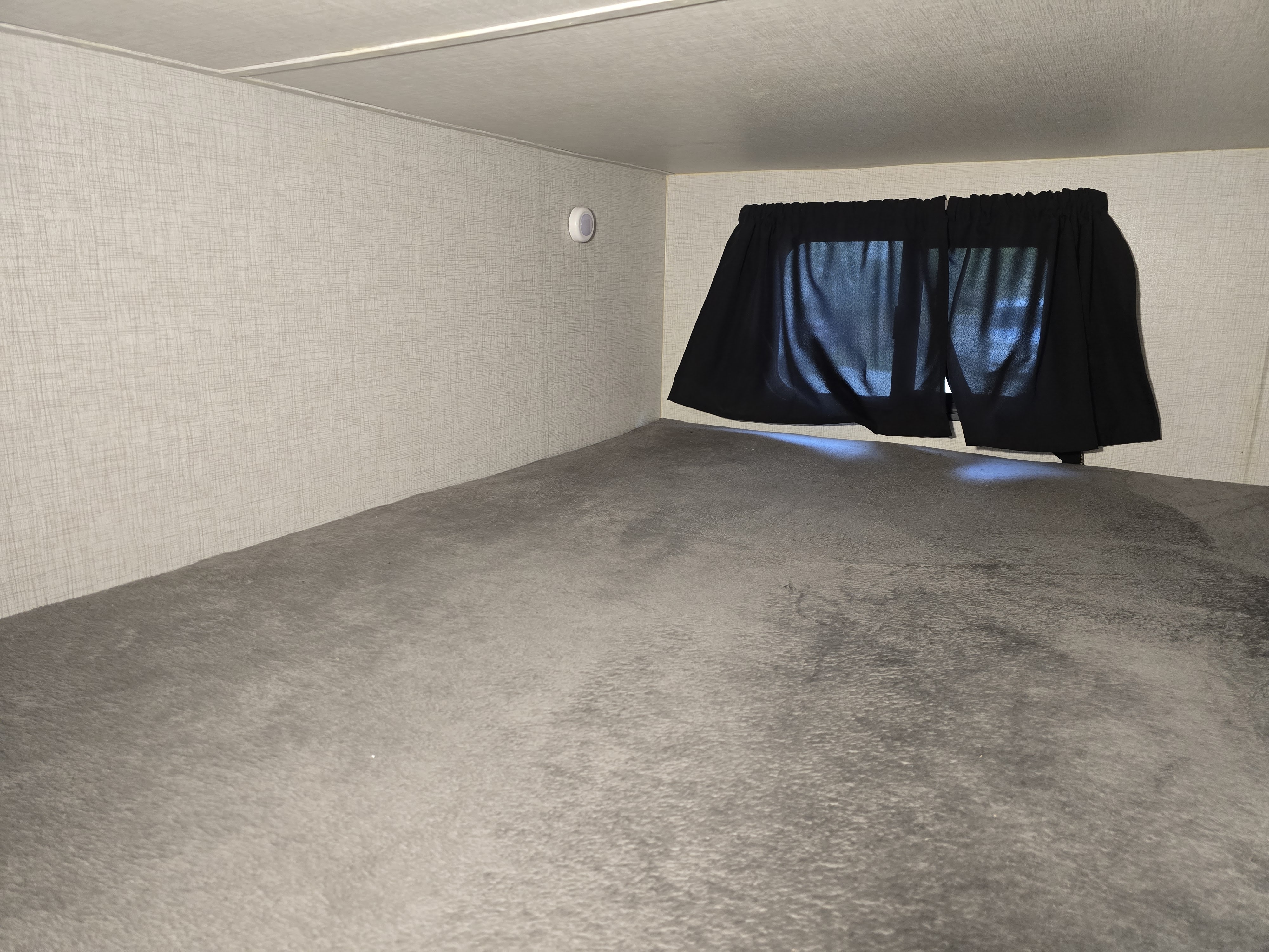 RV rental interior: A clean bunk bed area with light textured walls, dark curtains, and soft grey flooring, ideal for travel.. Crossroads RV Sunset Trail Super Lite 2021