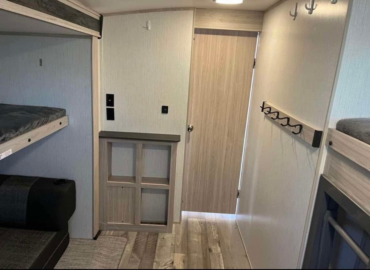 Inside an RV rental: bunk beds, sofa, storage, and a door reveal a cozy, functional space for travel adventures.. Heartland Sundance 2022