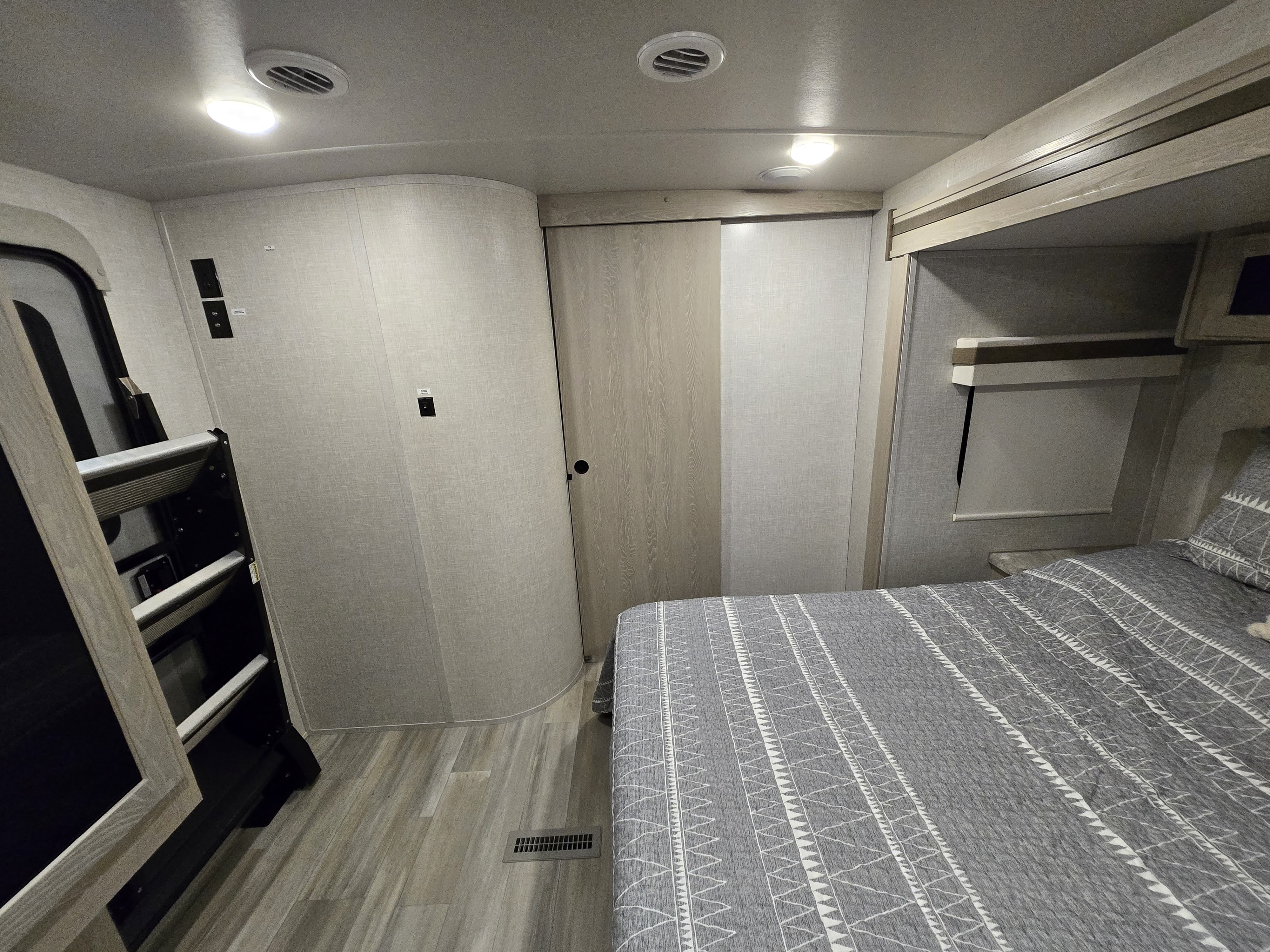 Inside an RV rental: a comfortable bedroom with patterned bed, sliding closet, and bunk access.. Forest River Rockwood Ultra Lite 2022