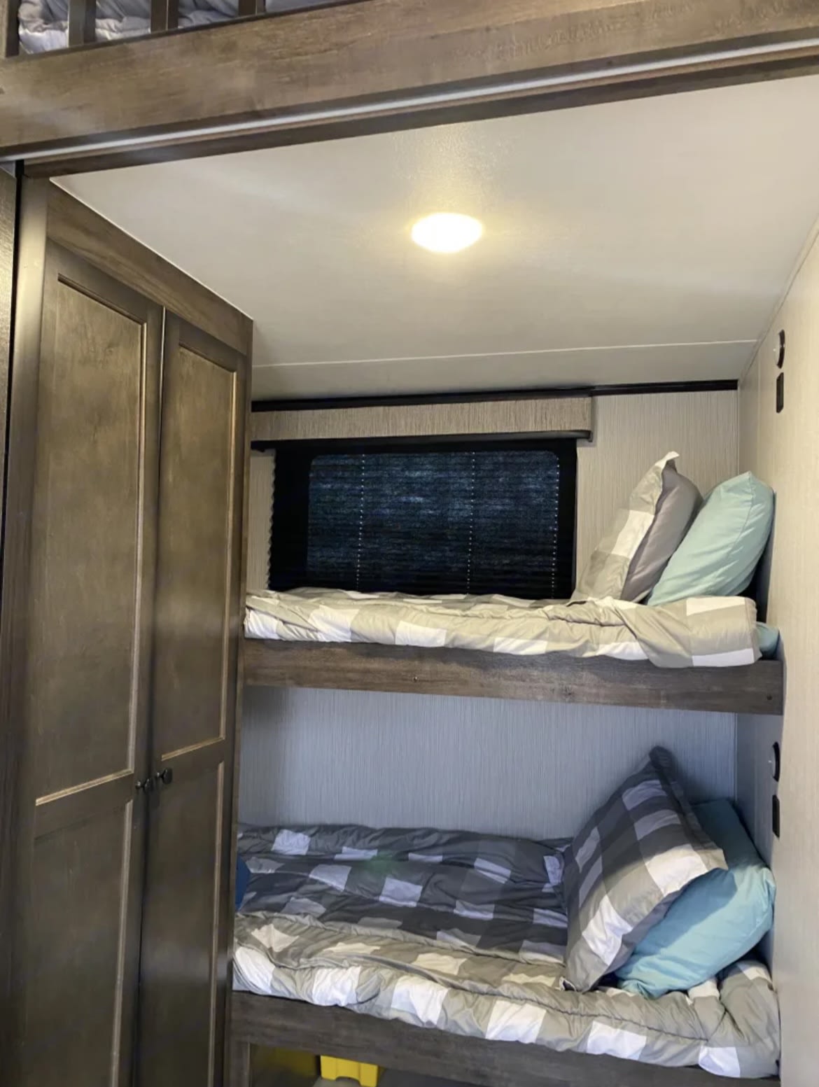 Cozy RV rental bunk beds with window, closet, and ceiling light. Perfect sleeping area for mobile living.. heartland Milestone 2021