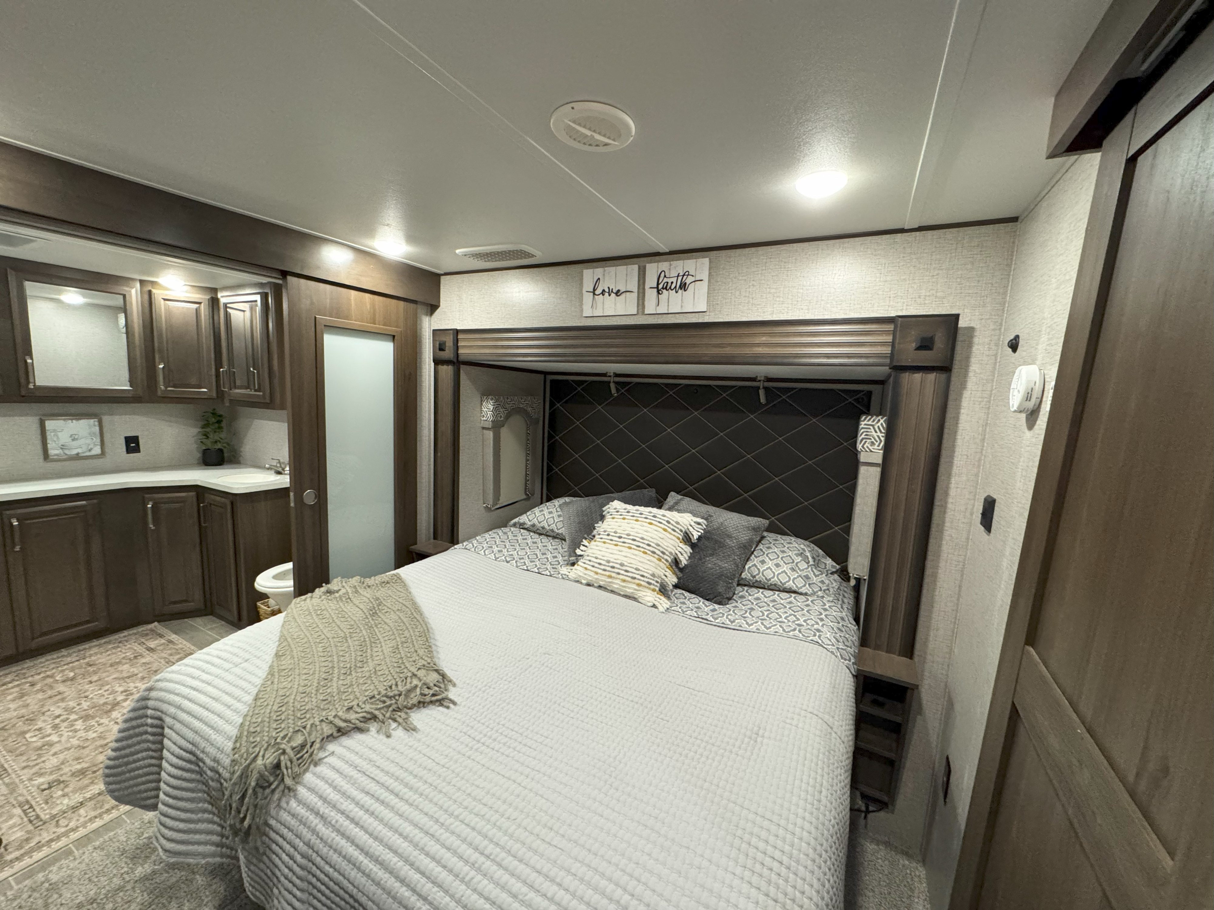 Modern RV rental bedroom featuring a comfy bed, stylish headboard, and an integrated private bathroom.. Keystone RV Alpine 2020