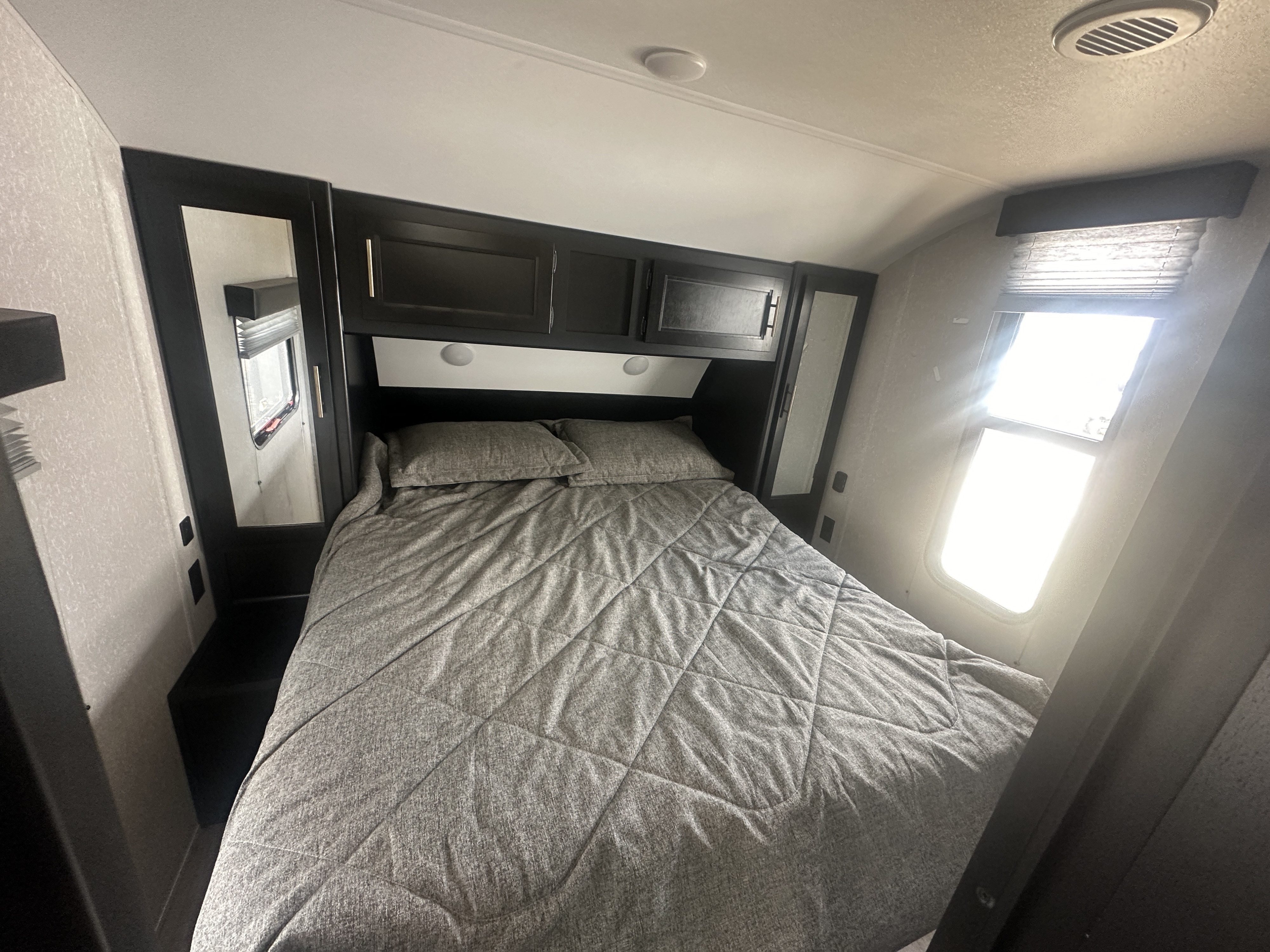 RV rental bedroom: cozy bed, overhead storage, and bright window. Perfect for your next travel adventure.. Forest River Cherokee Grey Wolf 2022