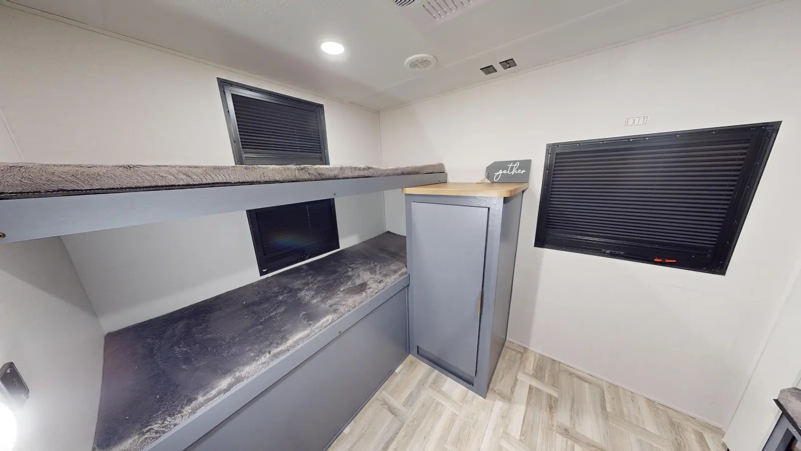 This RV rental interior shows two grey bunk beds, a storage cabinet, and windows with blinds, ideal for a comfortable stay.. Prime Time Tracer 2025