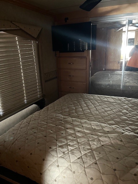Inside an RV rental: cozy bedroom with quilted bed, TV, dresser, and mirrored closet door. Your perfect escape.. Fleetwood Revolution 2005