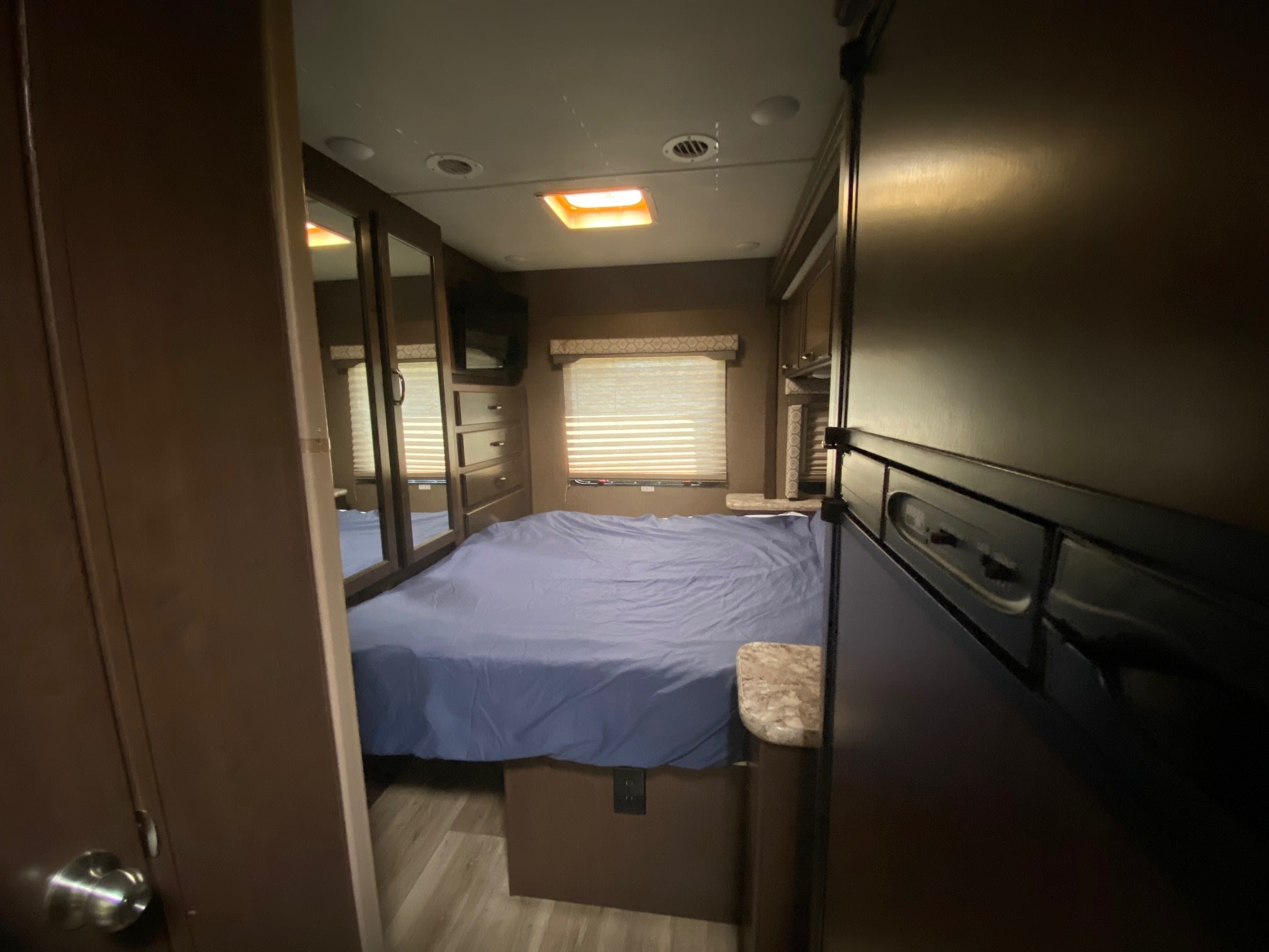 Experience comfort in this RV rental bedroom, featuring a cozy bed, mirrored closet, and window, ideal for travel.. Thor Freedom Elite 2018