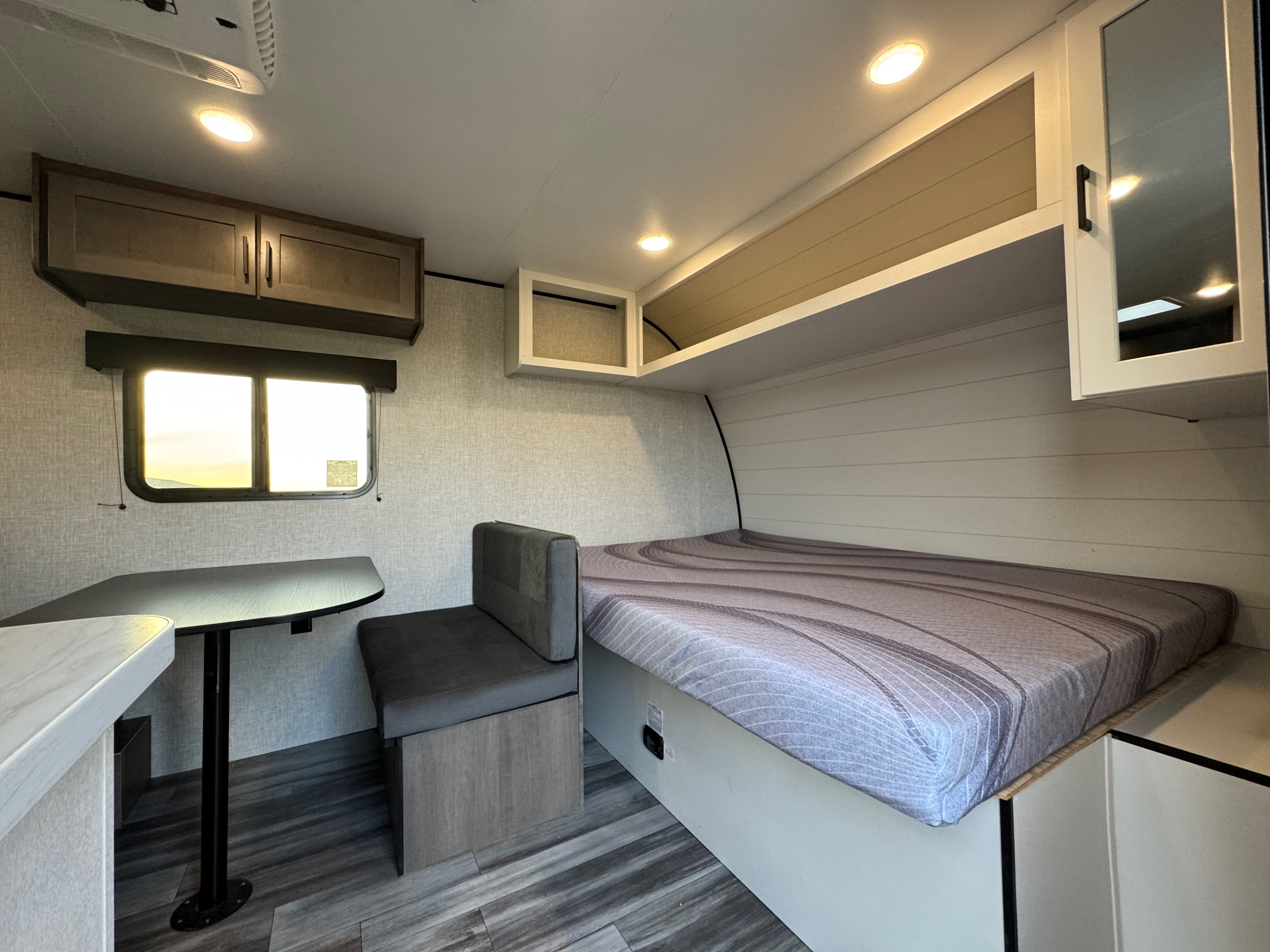 Cozy RV rental interior with a comfy bed, dinette, and overhead storage. Ideal for road trip adventures.. Jayco Jay Flight 2025