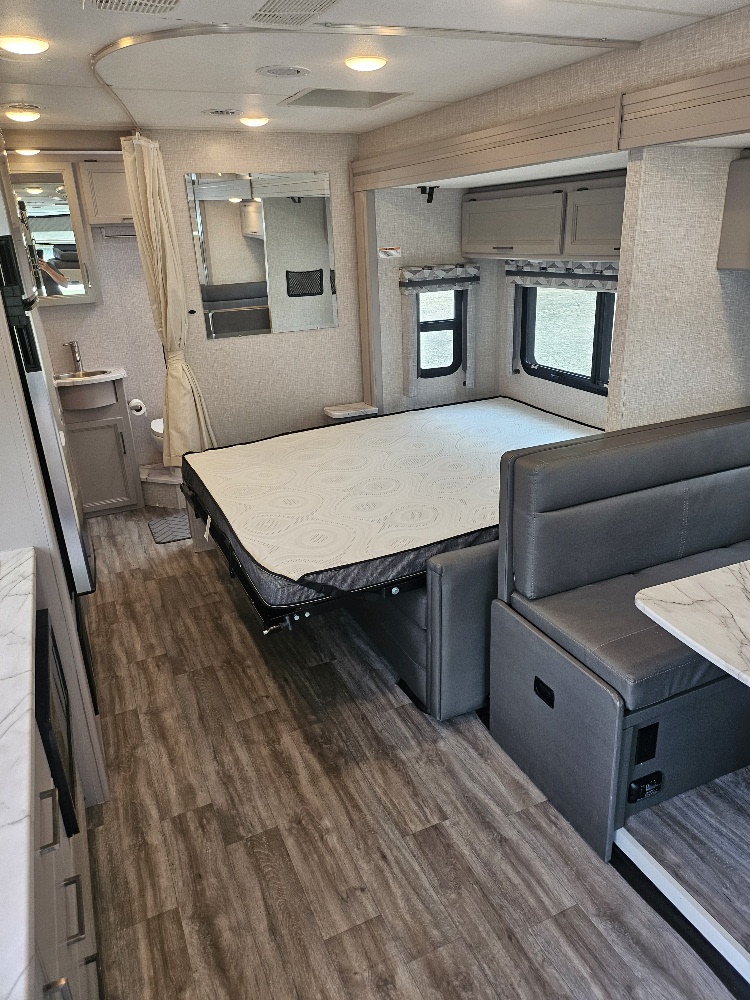 RV rental interior: versatile space with fold-down bed, dinette, wood-look floor & compact bathroom. Great for travel.. Thor Motor Coach Vegas 2024