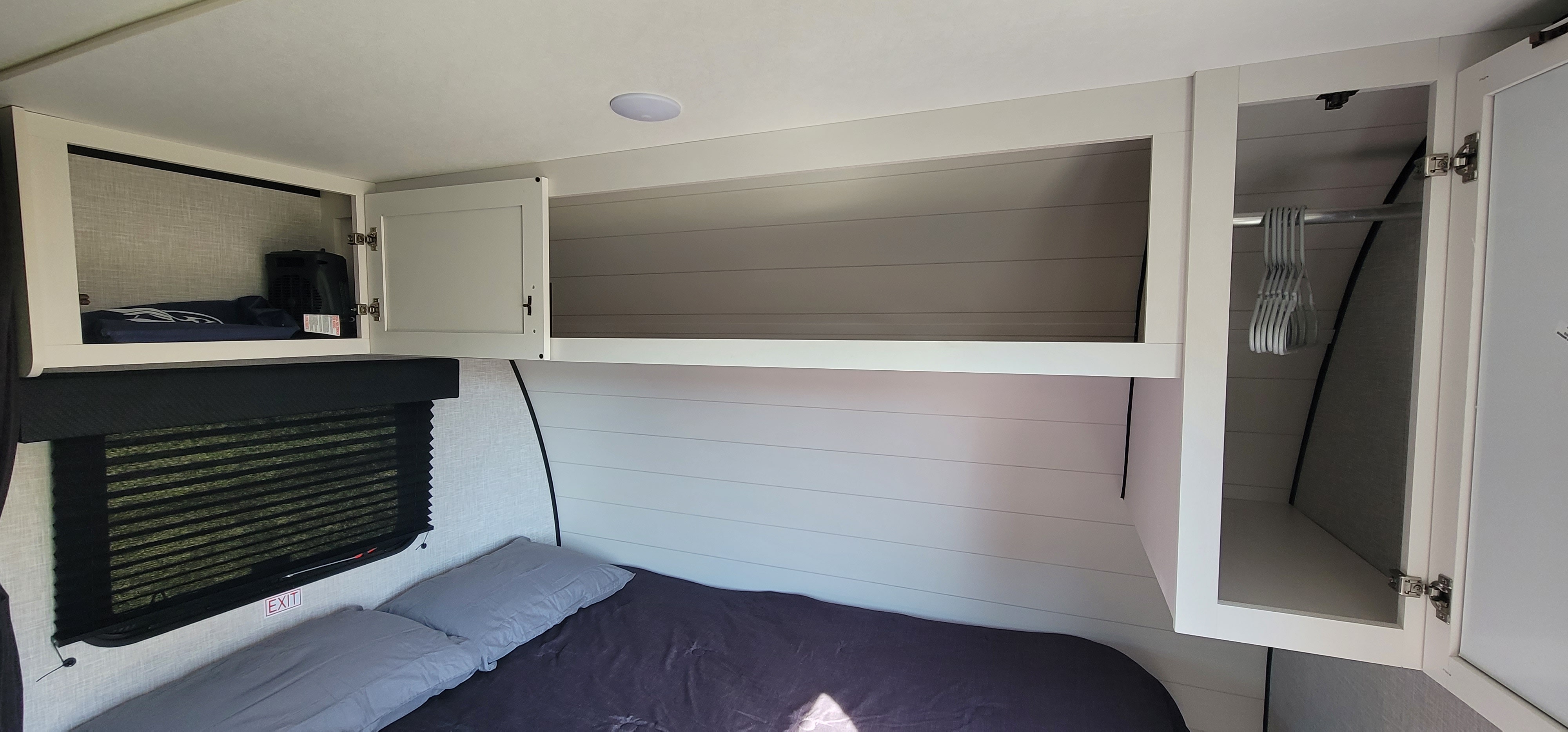 Cozy RV rental bedroom featuring an open overhead storage shelf, closed cabinets, a window, and a comfortable bed.. Jayco Jay Flight SLX 2025