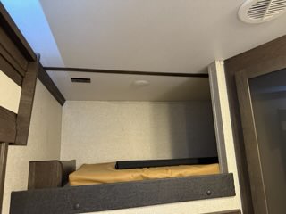 Inside an RV rental: a comfortable upper bunk bed with mattress, ready for an easy night's sleep in your recreational vehicle.. Keystone Raptor 2019