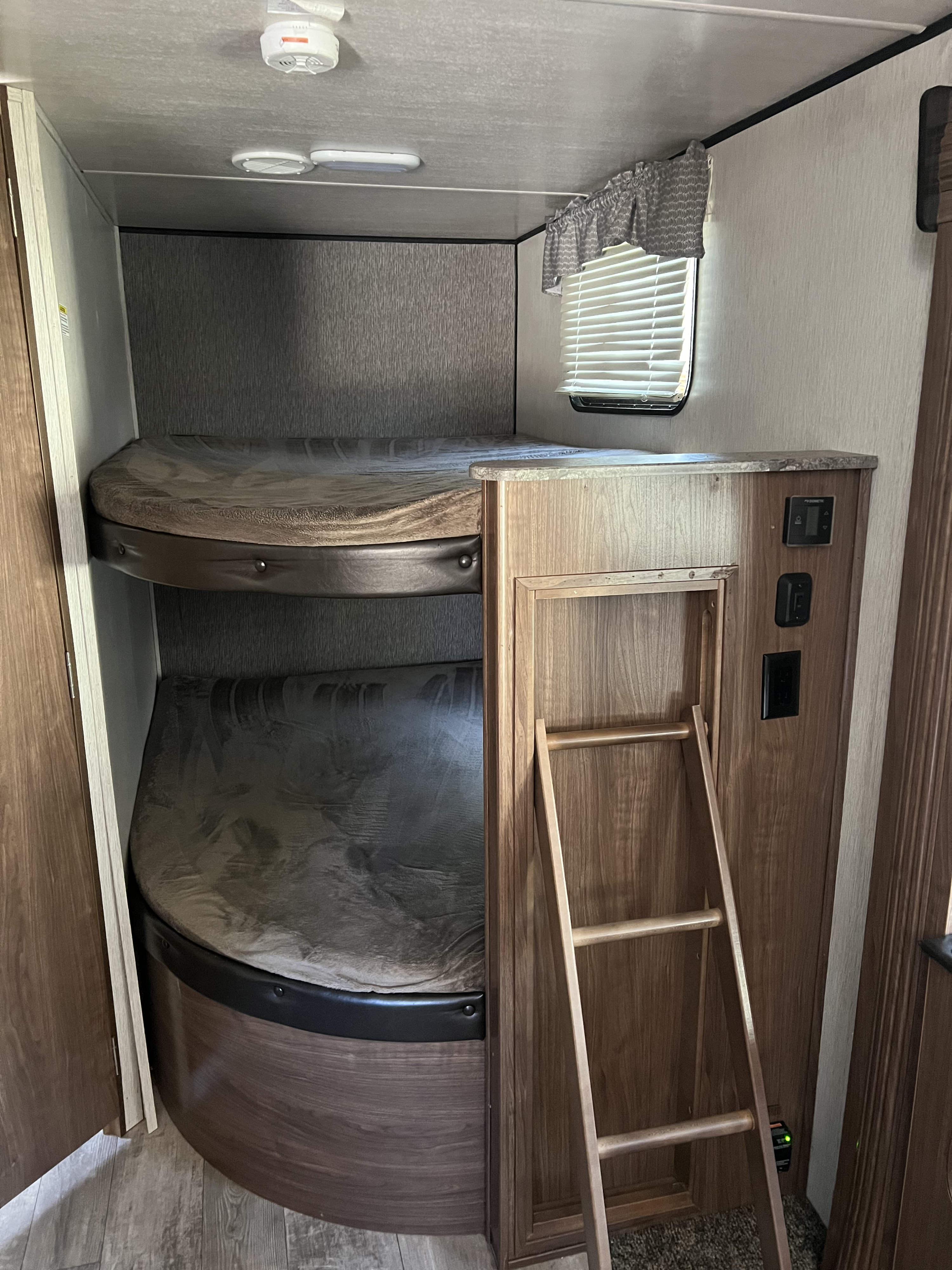 RV rental interior showing cozy bunk beds with mattresses & a ladder for easy access. Ideal sleeping area in a travel trailer.. Heartland RVs Pioneer 2018
