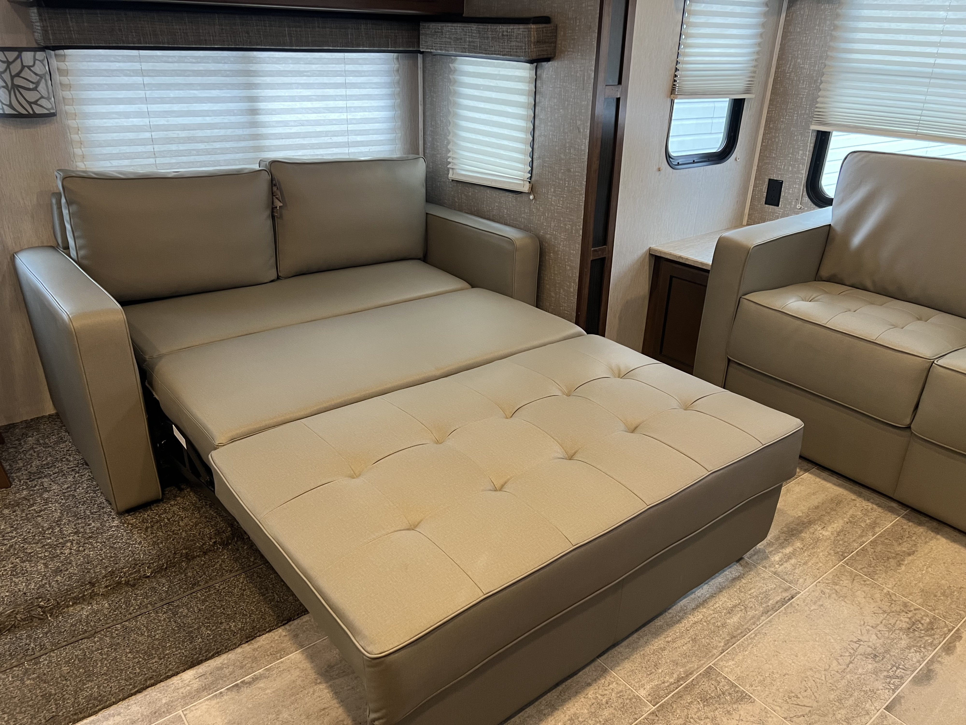 This RV rental interior features a functional, neutral-toned sofa bed extended for sleeping, maximizing the compact living area.. Heartland RVs Mallard 2019