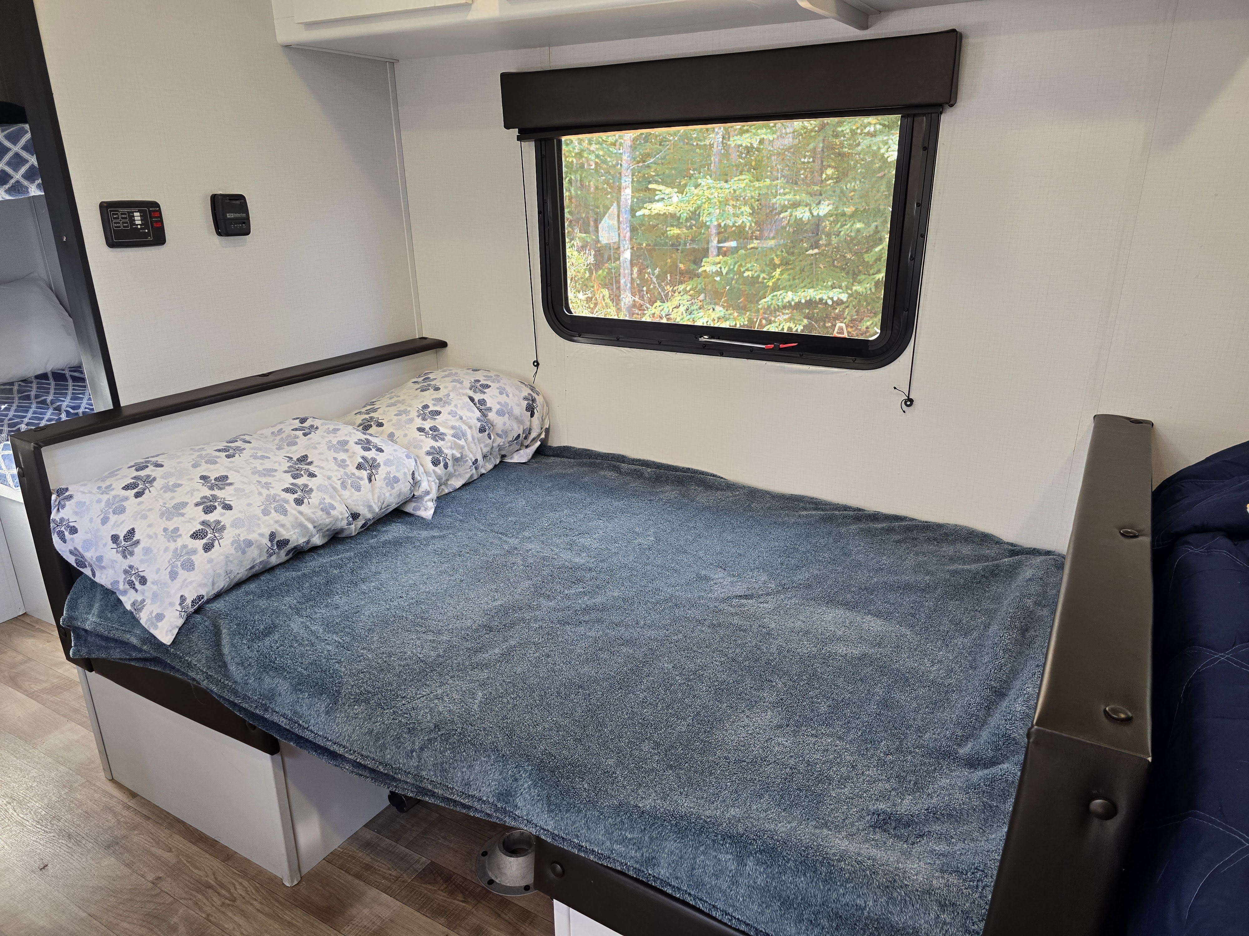 A comfortable sleeping area in an RV rental, featuring a window with nature views and interior control panels.. Keystone RV Hideout 2022