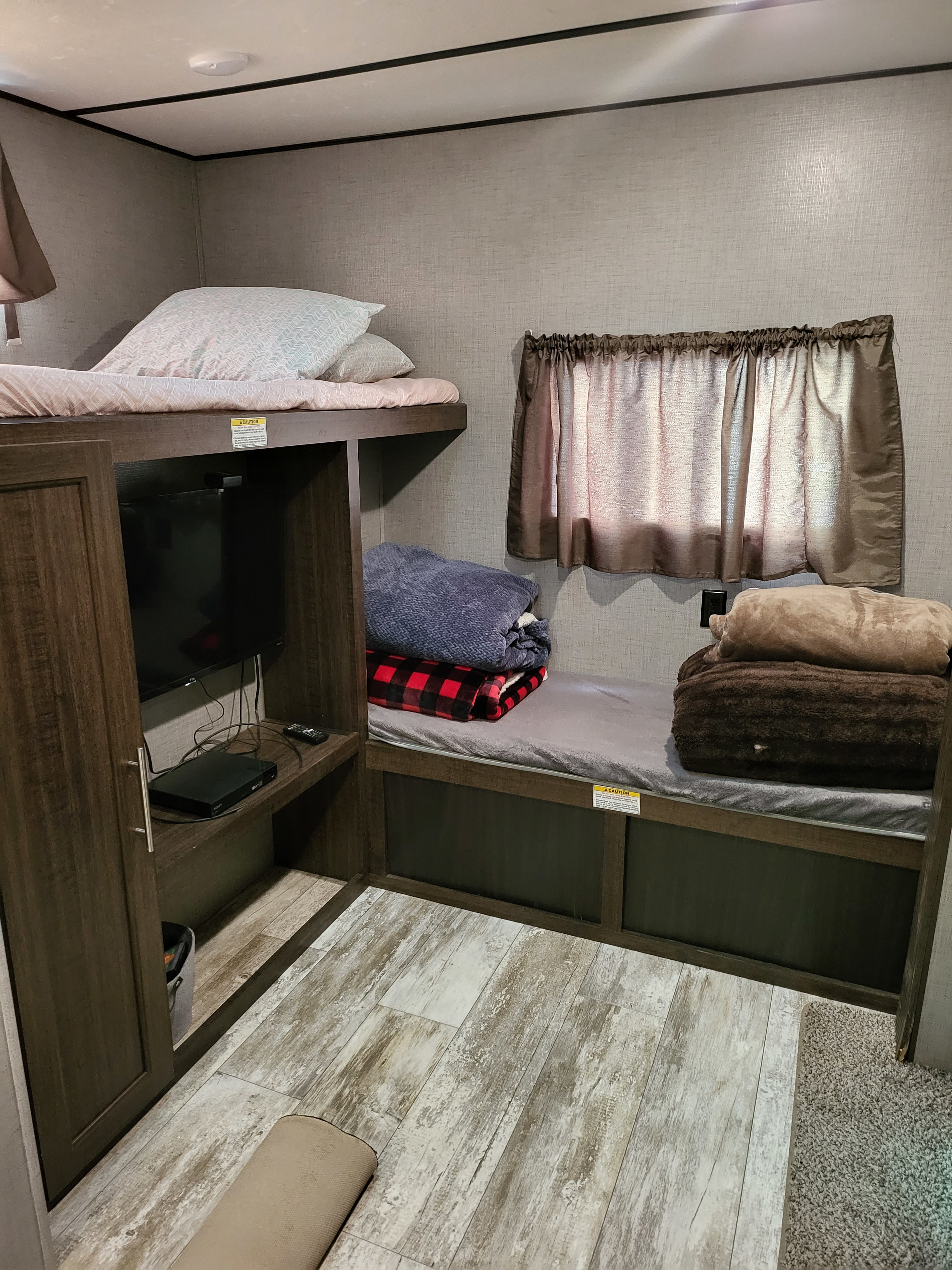 Cozy RV rental bunk room features stacked beds, a TV, and storage for a comfortable travel stay.. Crossroads RV Zinger 2020