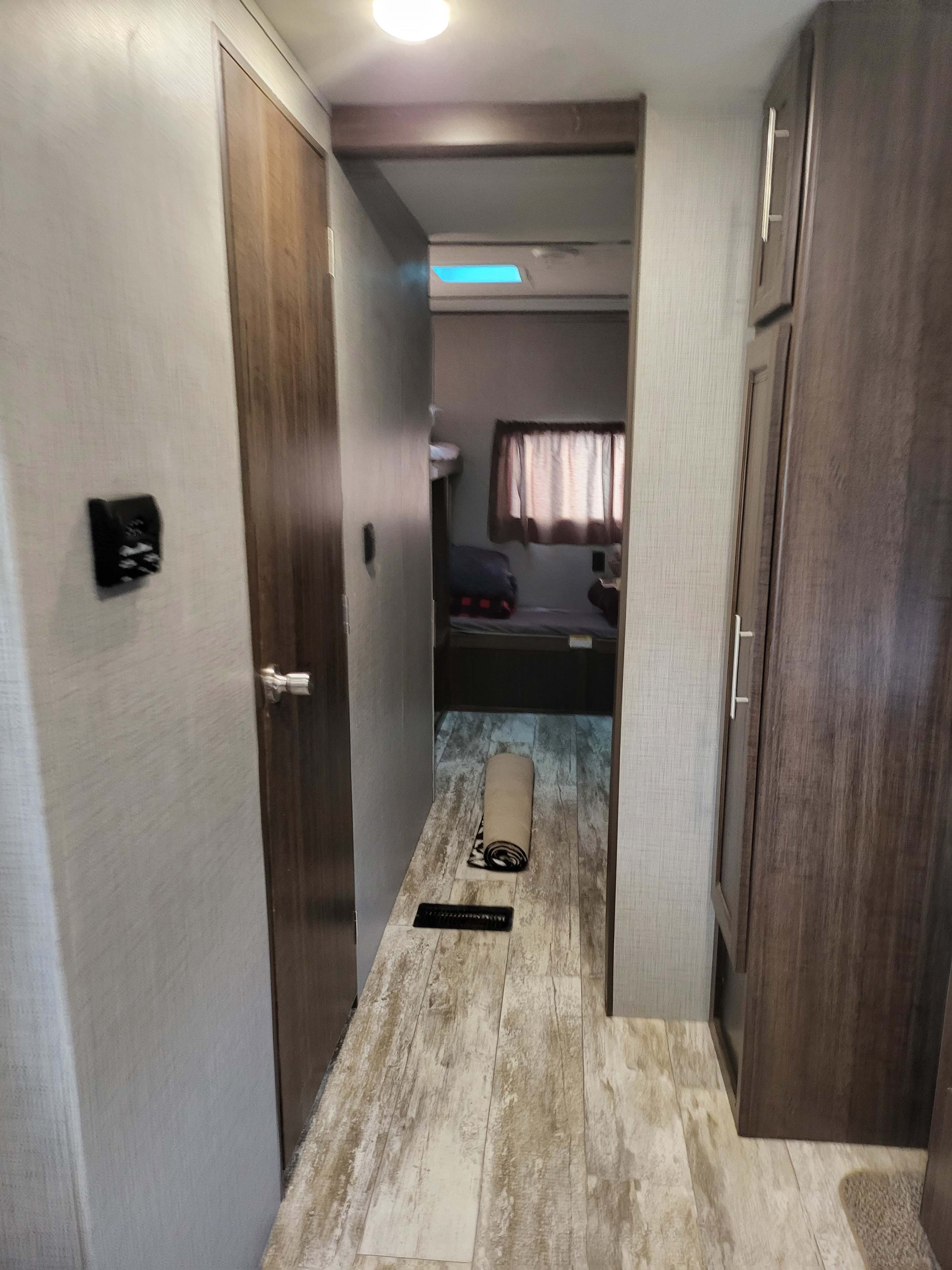 Step inside this RV rental! The hallway features wood-look flooring, a control panel, and leads to a cozy bunk room.. Crossroads RV Zinger 2020