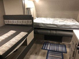 This RV rental interior features a cozy dinette (left) and a spacious elevated bed (right), offering comfy sleeping options.. Coachmen Coachmen Catalina Summit Series 7 184BHS 2022