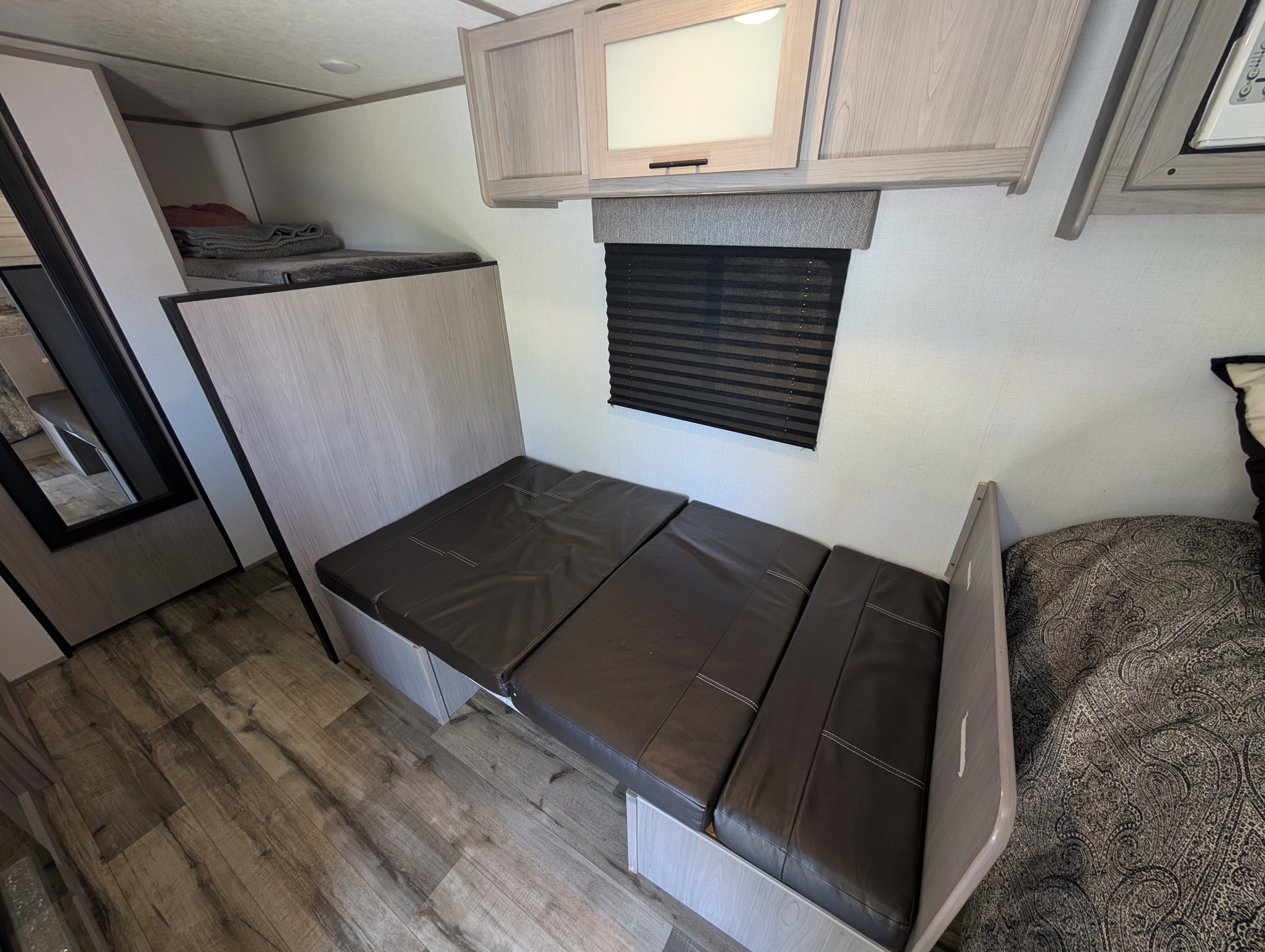 Comfortable RV rental interior with convertible dinette seating, an upper bunk bed, and ample storage.. Keystone RV Coleman Lantern 17b 2024