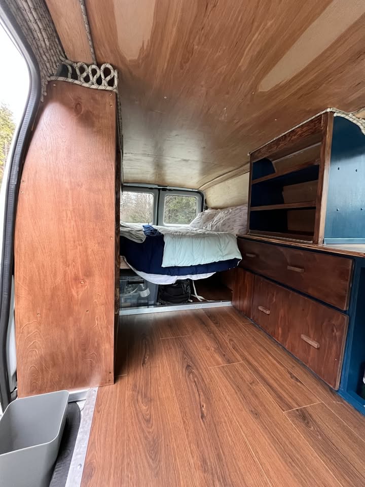 Step inside this cozy RV rental camper van featuring wood interiors, bed, and storage for your journey.. Ford Ford E350 2006