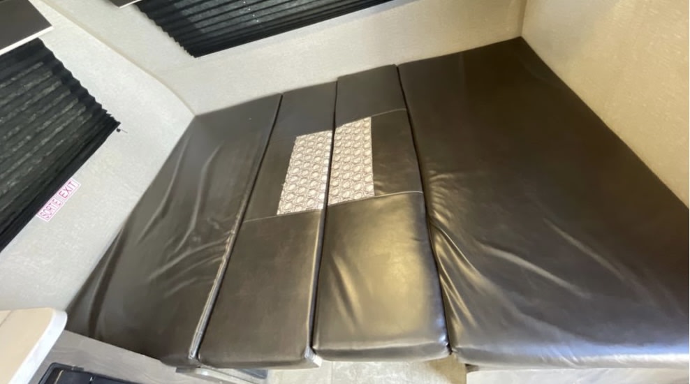 RV rental interior: A flexible dinette area with dark cushions converts to a comfortable bed, marked by a 'SORTE EXIT' sign.. Jayco Baja 2021