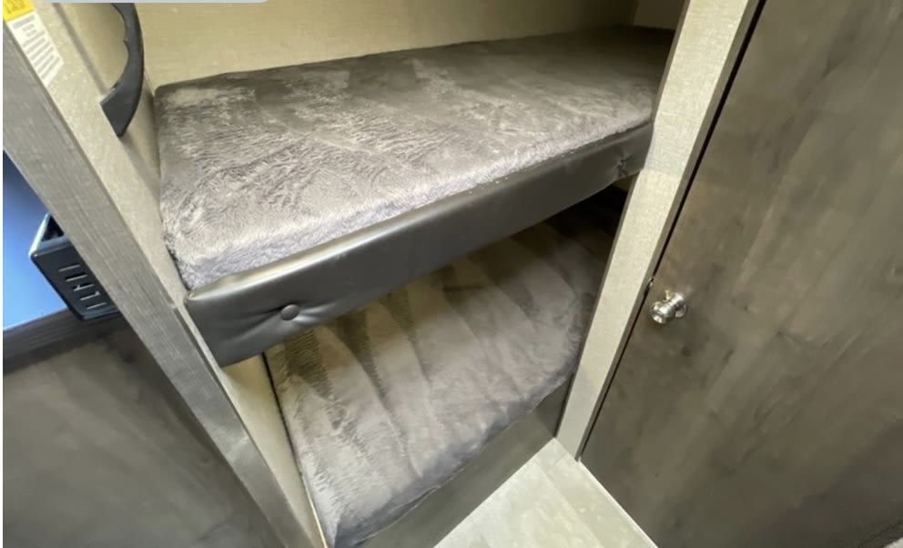 Cozy bunk beds in an RV rental, featuring plush grey mattresses and compact sleeping arrangements for guests.. Jayco Baja 2021