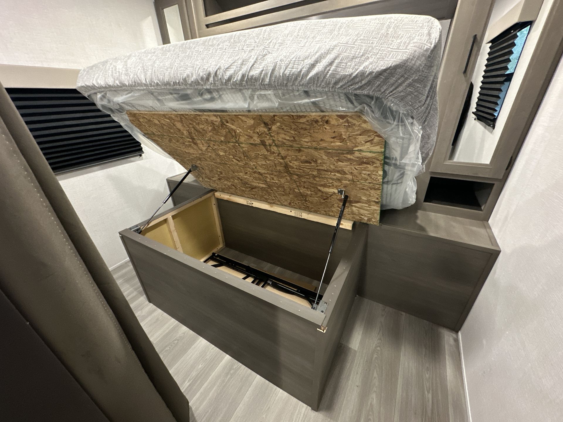 RV rental: Bed with mattress lifted by gas struts, revealing deep under-bed storage. Efficient space utilization.. Grand Design Transcend Xplor 2024