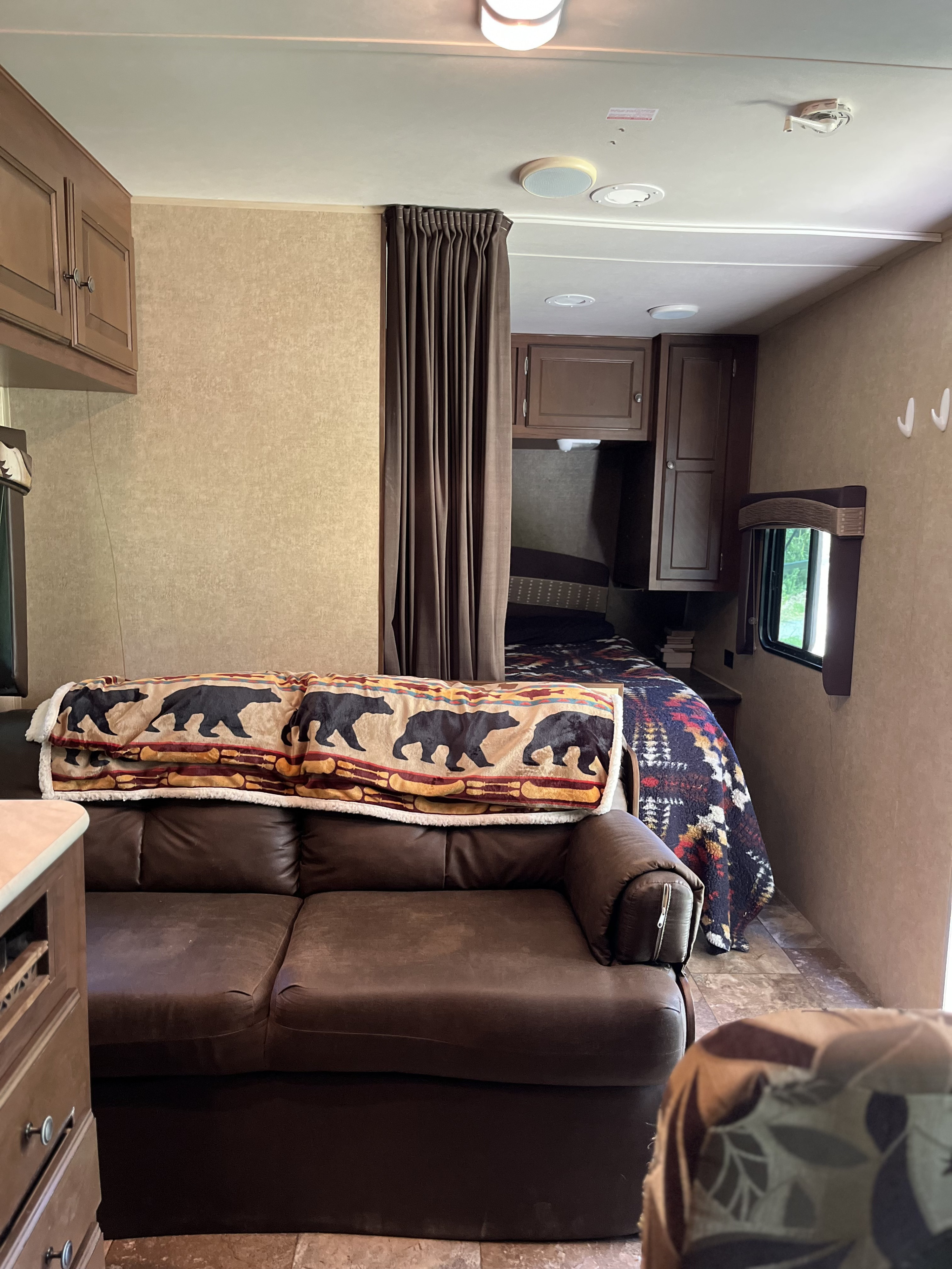 Welcoming RV rental interior featuring a comfy brown couch, bear blanket, and a cozy private bedroom.. Jayco Jay Flight 2014