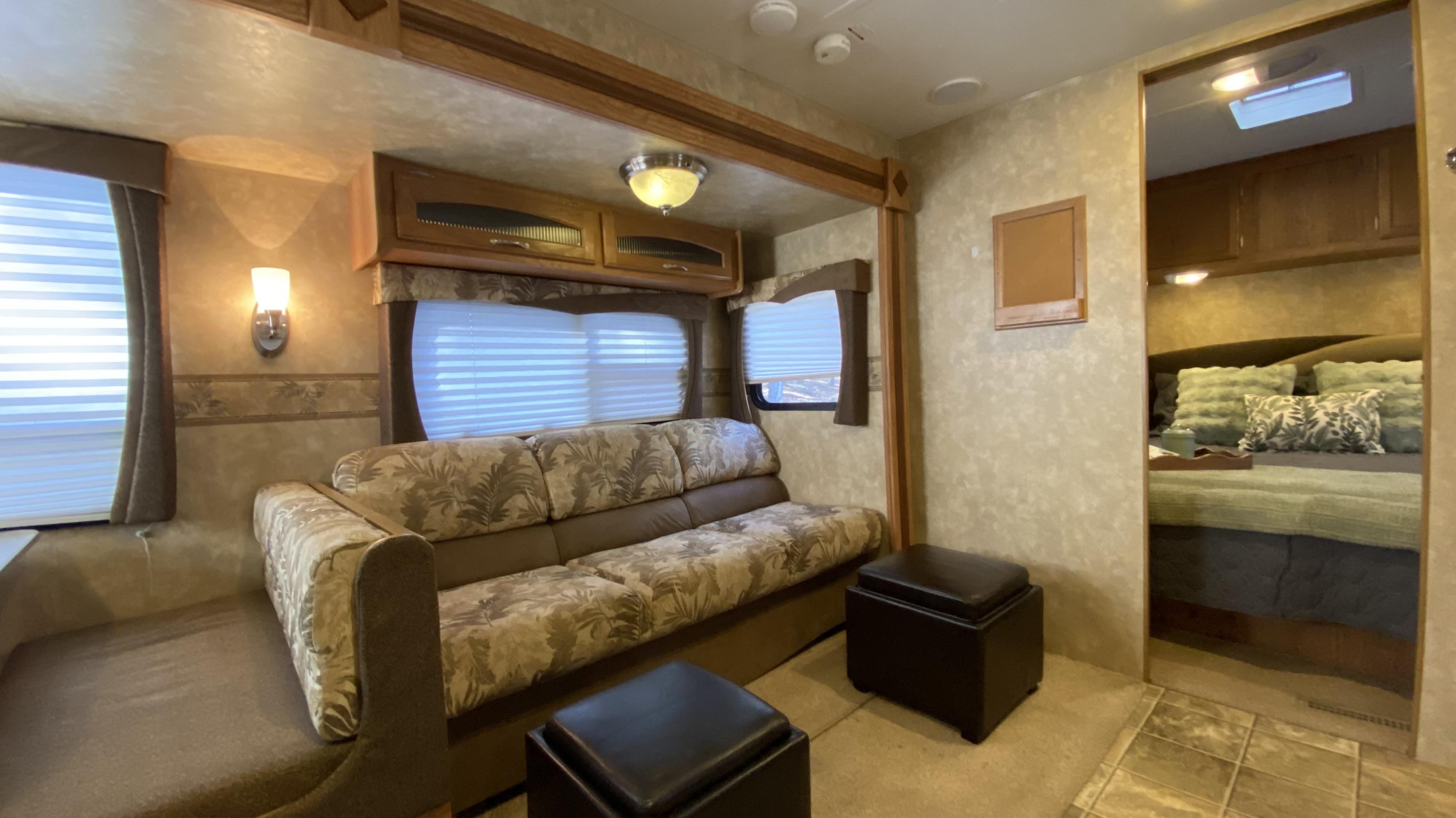Spacious RV rental living area with floral-patterned sofa, large windows, and an inviting doorway leading to the bedroom.. Jayco Jay Flight G2 2010