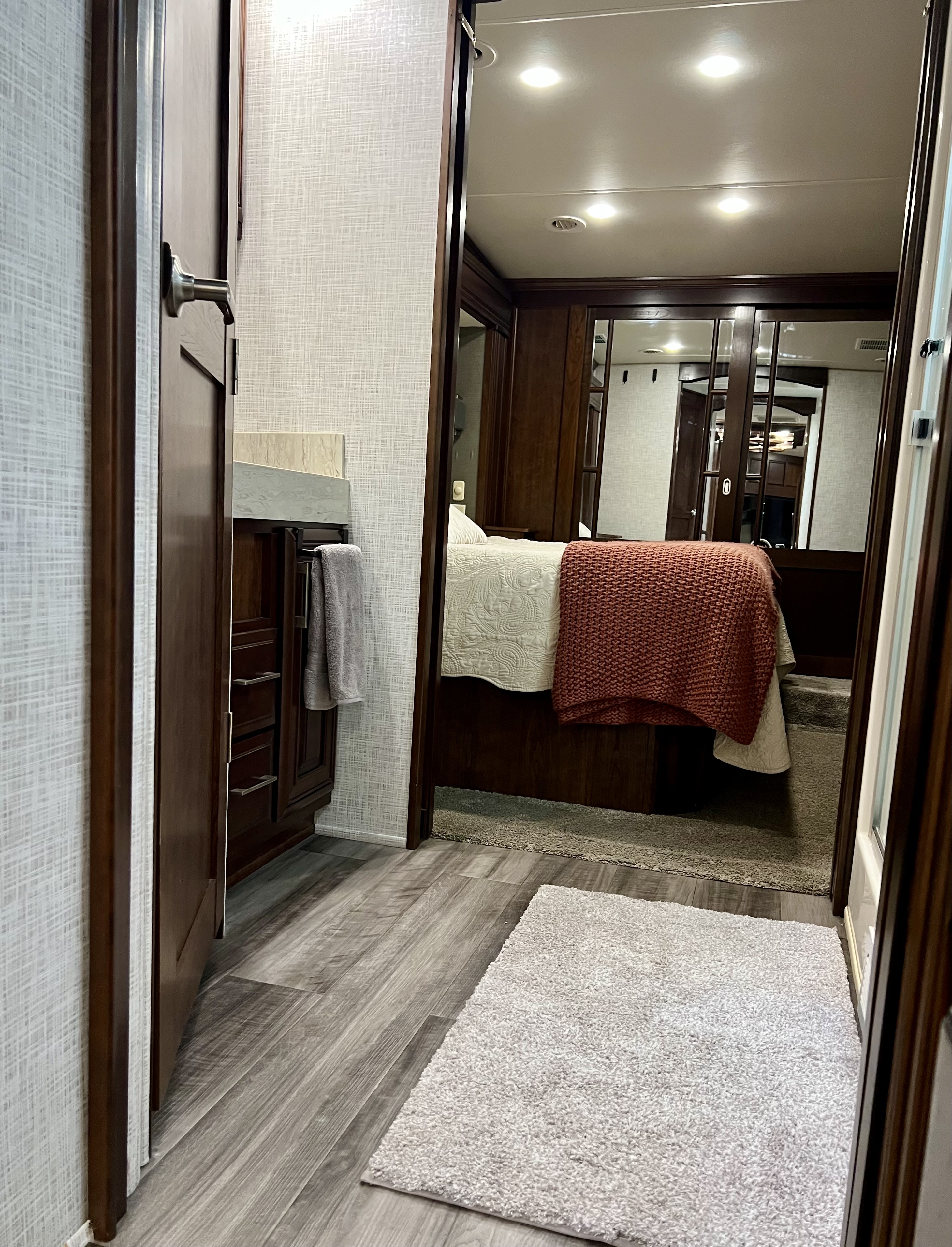 Step into comfort: an RV rental interior showing a vanity area and a cozy bedroom with modern wood finishes and soft bedding.. Drv Fullhouse LX455 2019