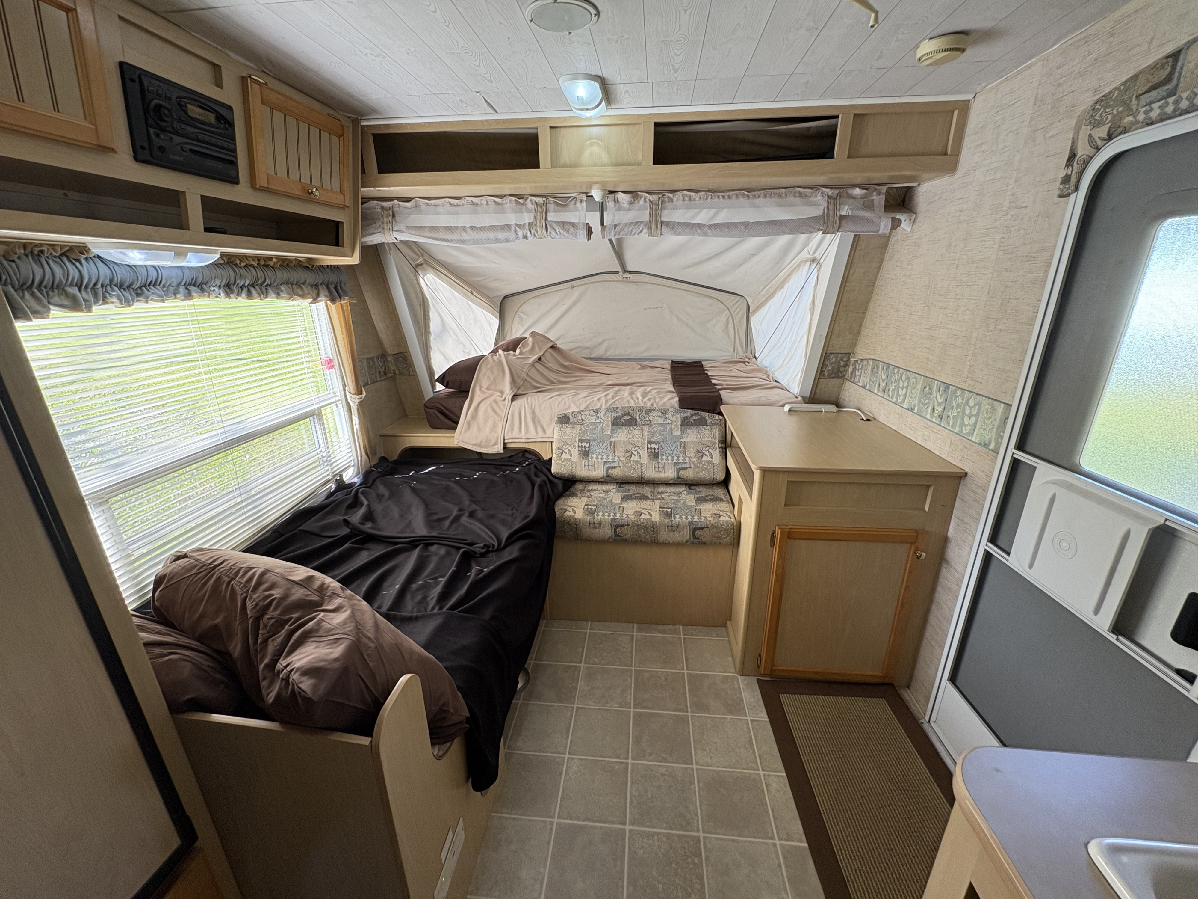 Step inside this RV rental: a compact camper interior with convertible beds, a dinette, and overhead storage, offering cozy living.. Jayco Jay Feather EXP 2005