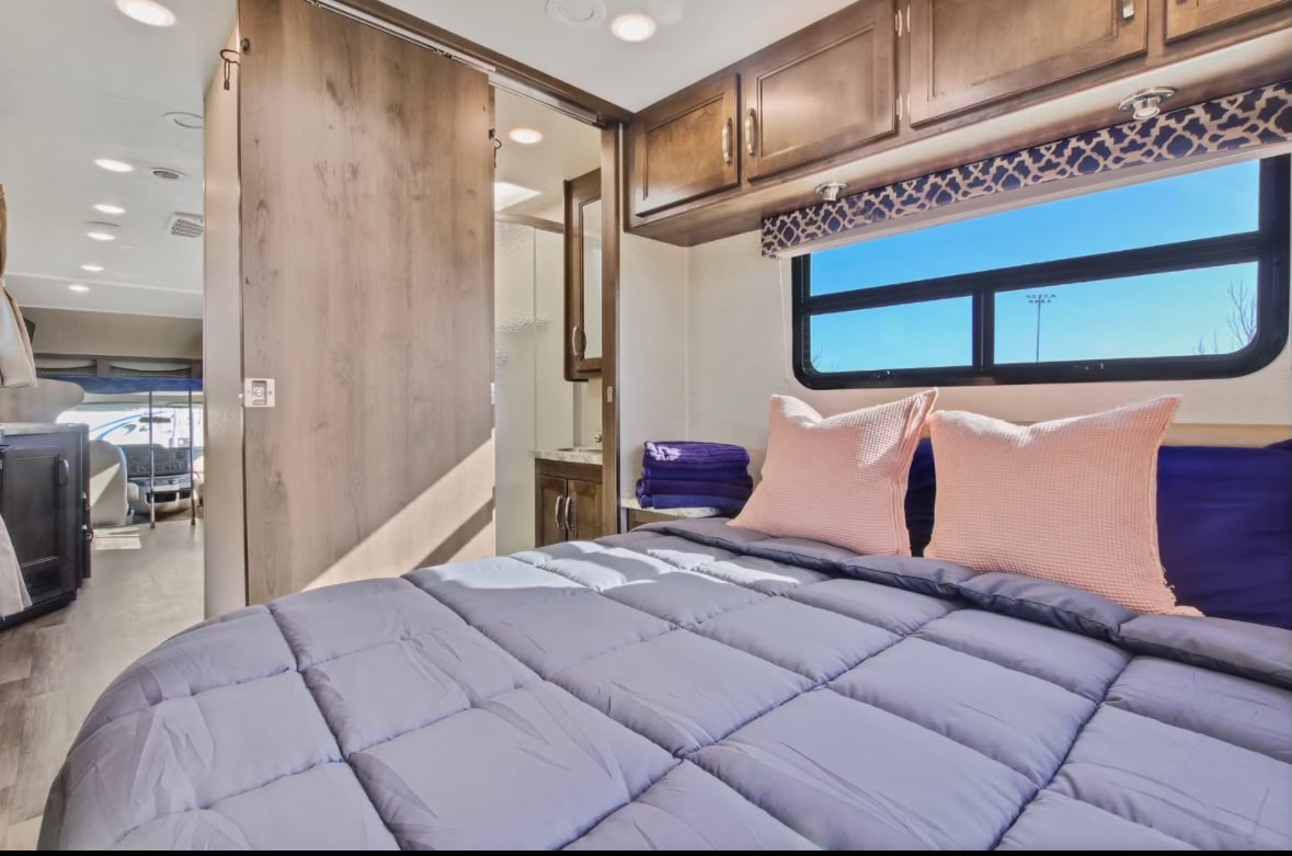 Cozy RV rental bedroom with a comfy bed, compact bathroom, and front cabin views for your next adventure.. Jayco Redhawk 2019