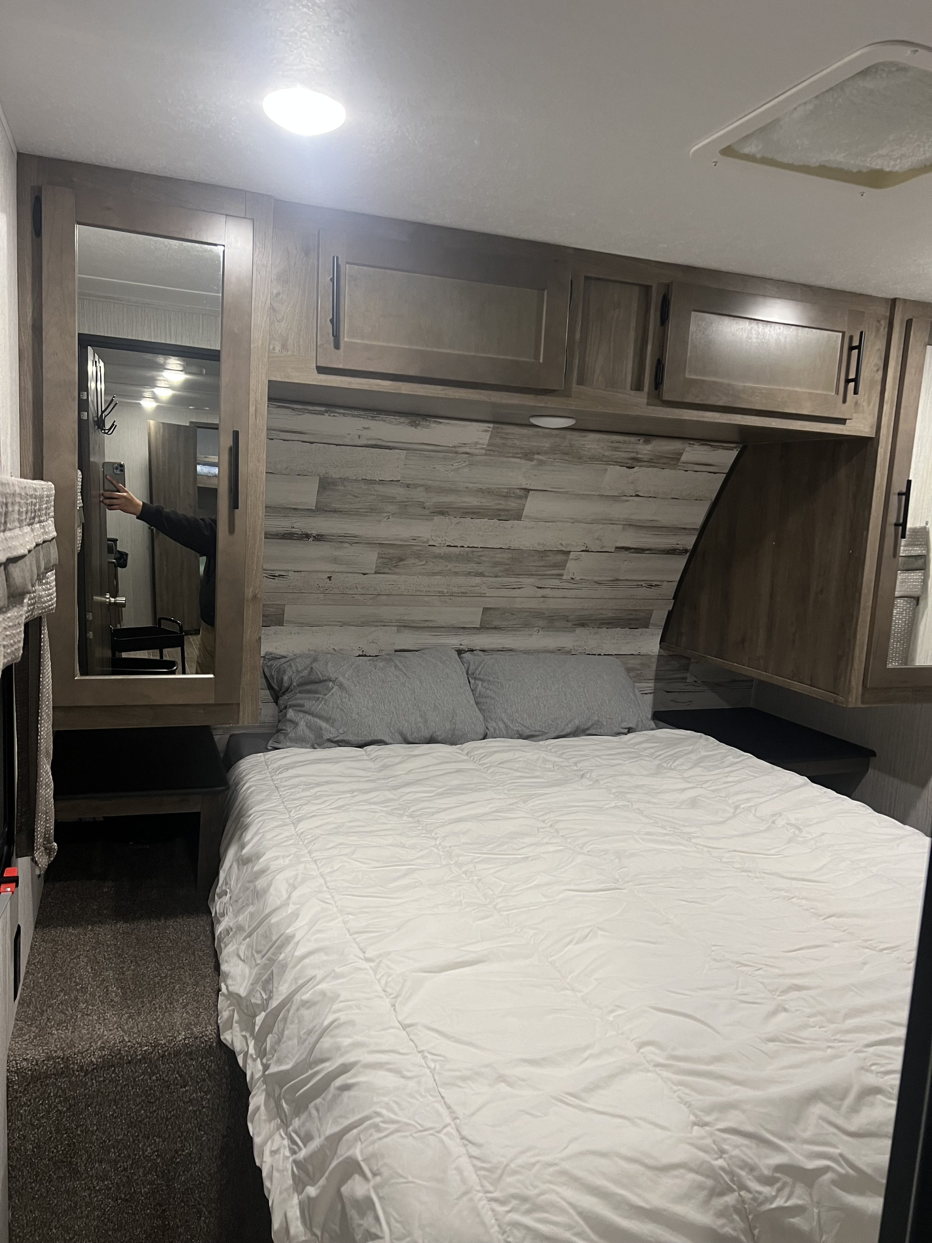 Compact RV rental bedroom with a comfy bed, overhead cabinets, and mirrored closet. Perfect for adventures.. Forest River Palomino Puma 2021