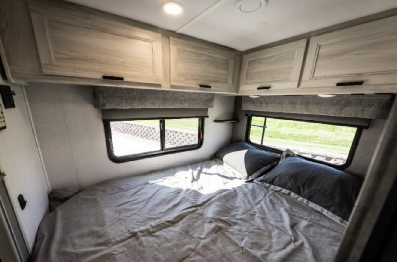 Comfortable RV rental bedroom with light wood cabinets, cozy bed, and windows. Perfect for travel.. Forest River Sunseeker LE 2022