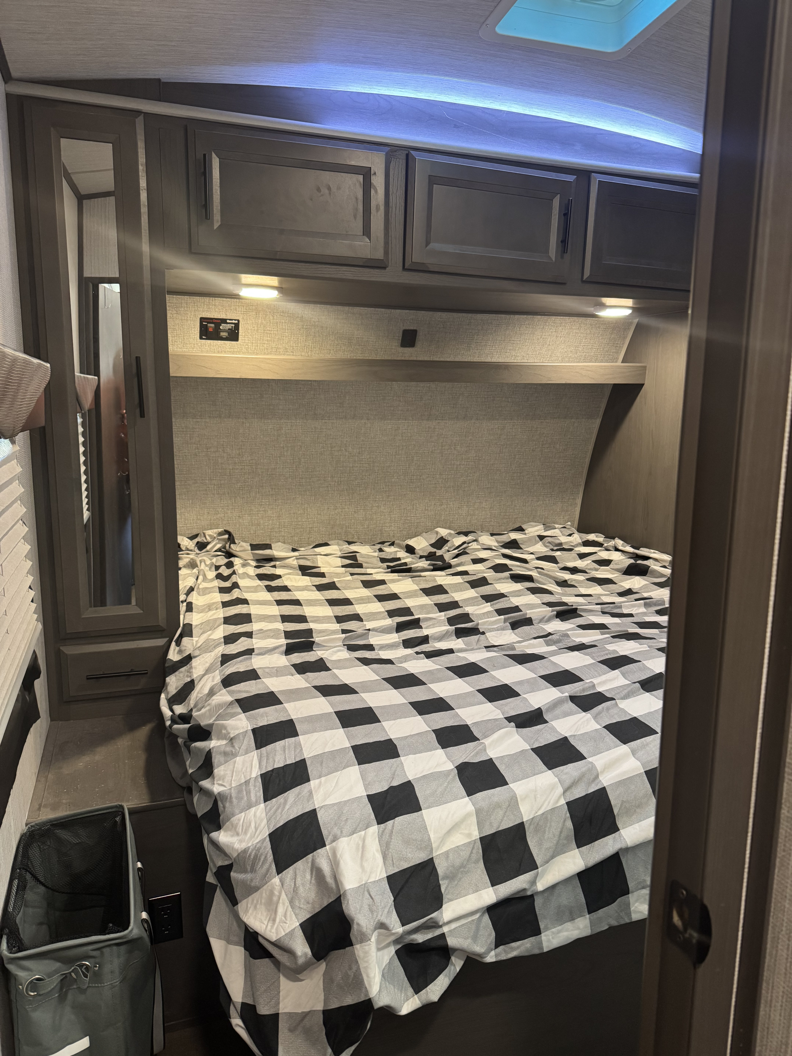 Cozy RV bedroom with checkered bedspread, overhead storage, and mirror. Perfect for your next rv rental adventure!. Cruiser Rv Corp Stryker 2020