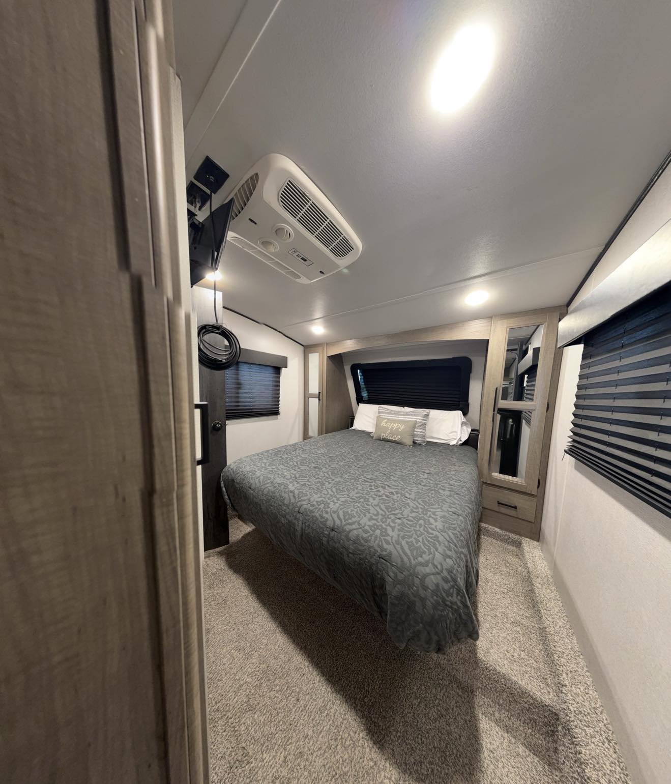 Spacious RV rental bedroom featuring a comfortable bed, overhead AC unit, and wall-mounted TV.. Keystone Hideout 2021