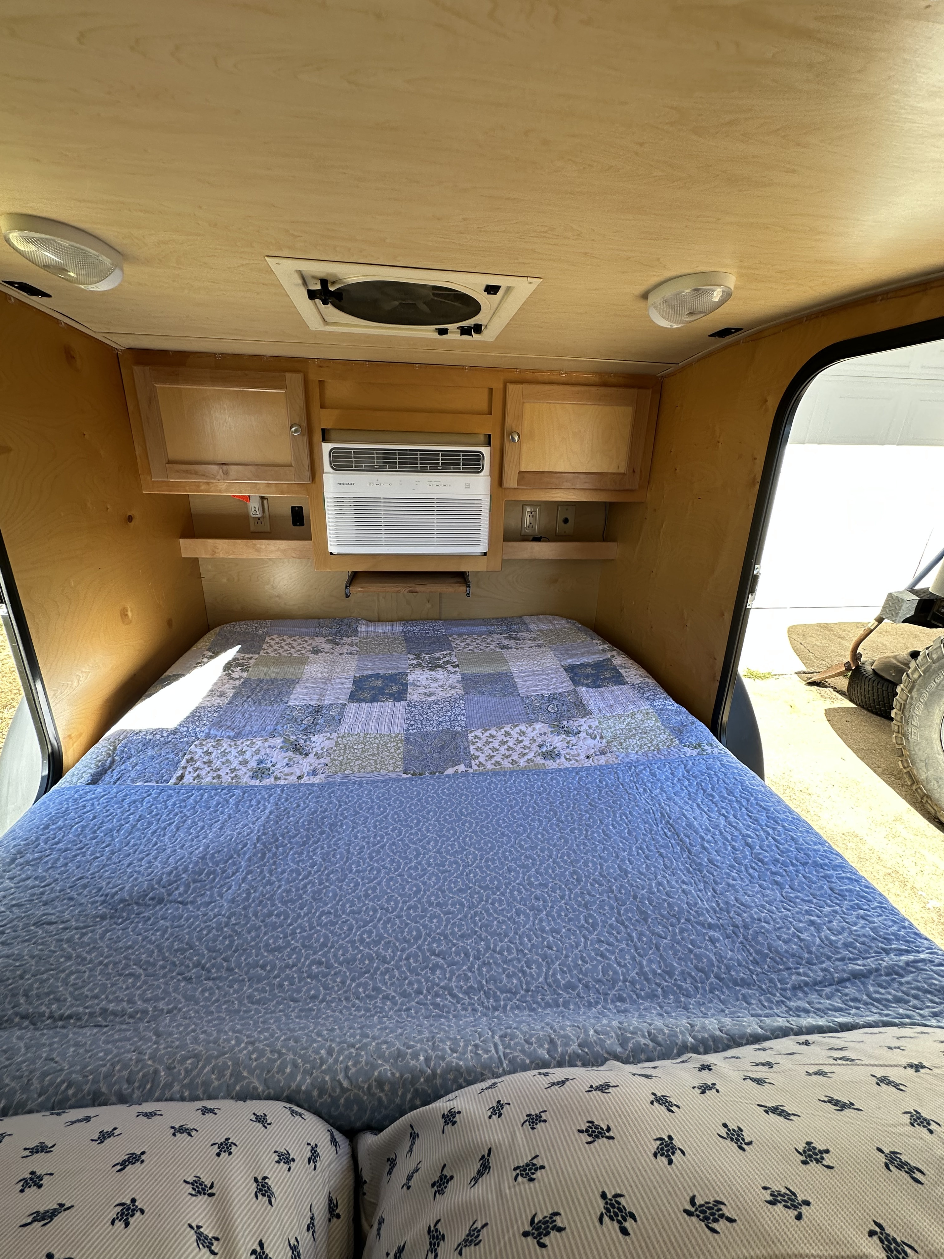 Relax in this RV rental's cozy bed! Features an AC unit, wooden interior, and bright lighting.. Little Guy Little Guy Trailer 2012