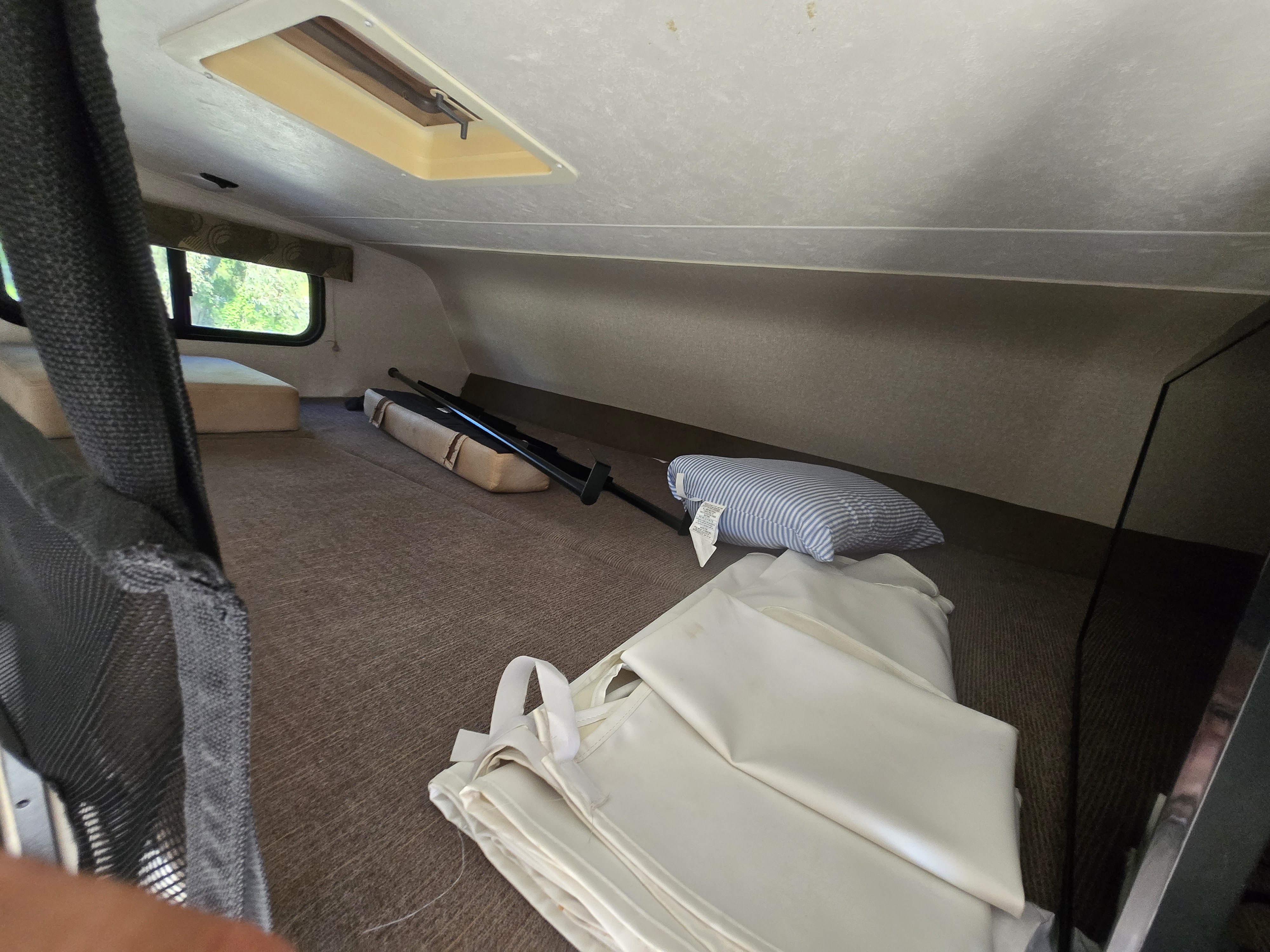 Explore your RV rental: a cozy over-cab loft with window, mattress, and safety netting for comfortable travel.. Forest River Coachmen Freelander 2019
