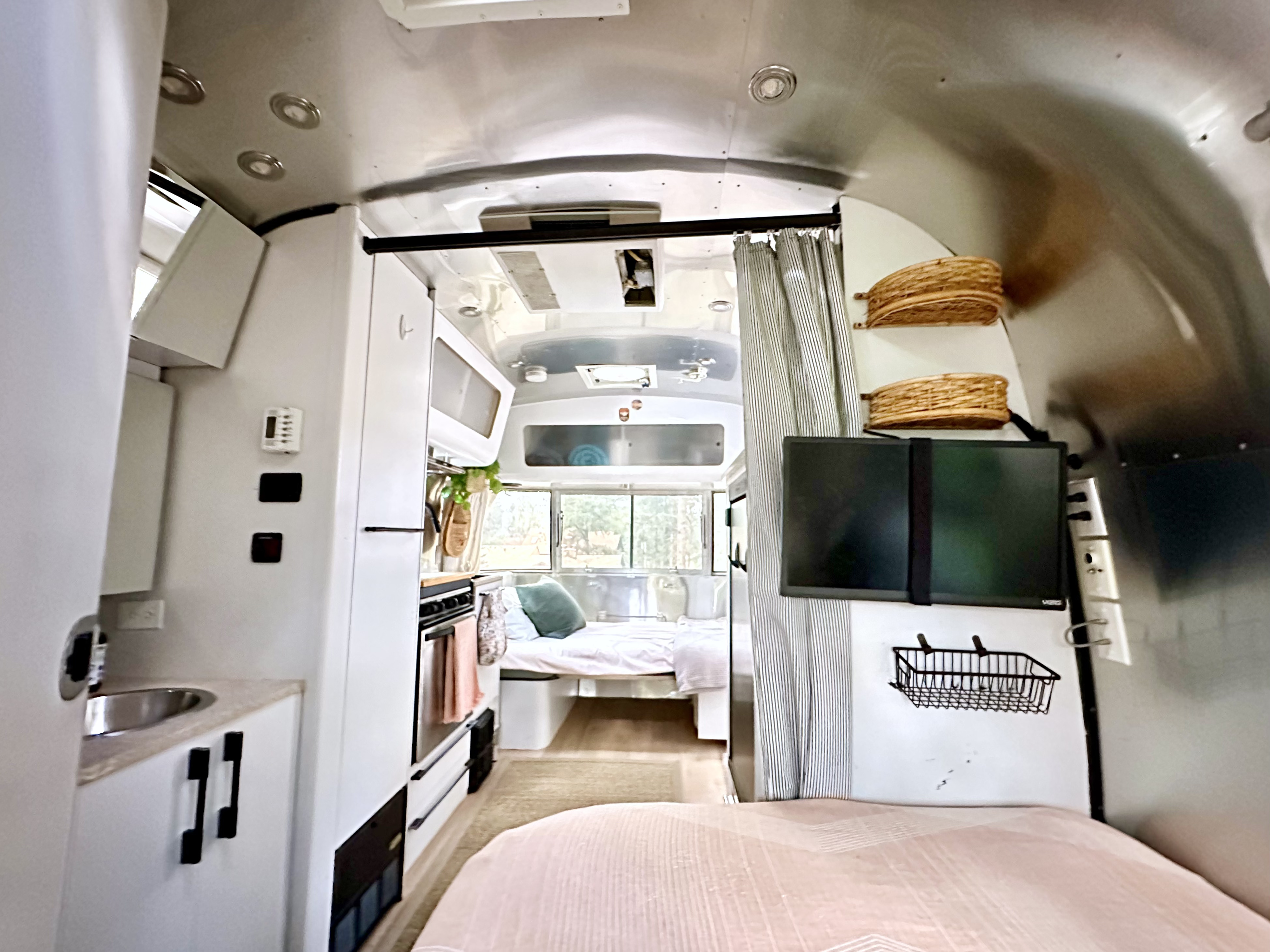 Inside a modern Airstream RV rental: sleek silver interior with kitchen, stove, sink, and comfy sleeping areas.. Airstream International 2008