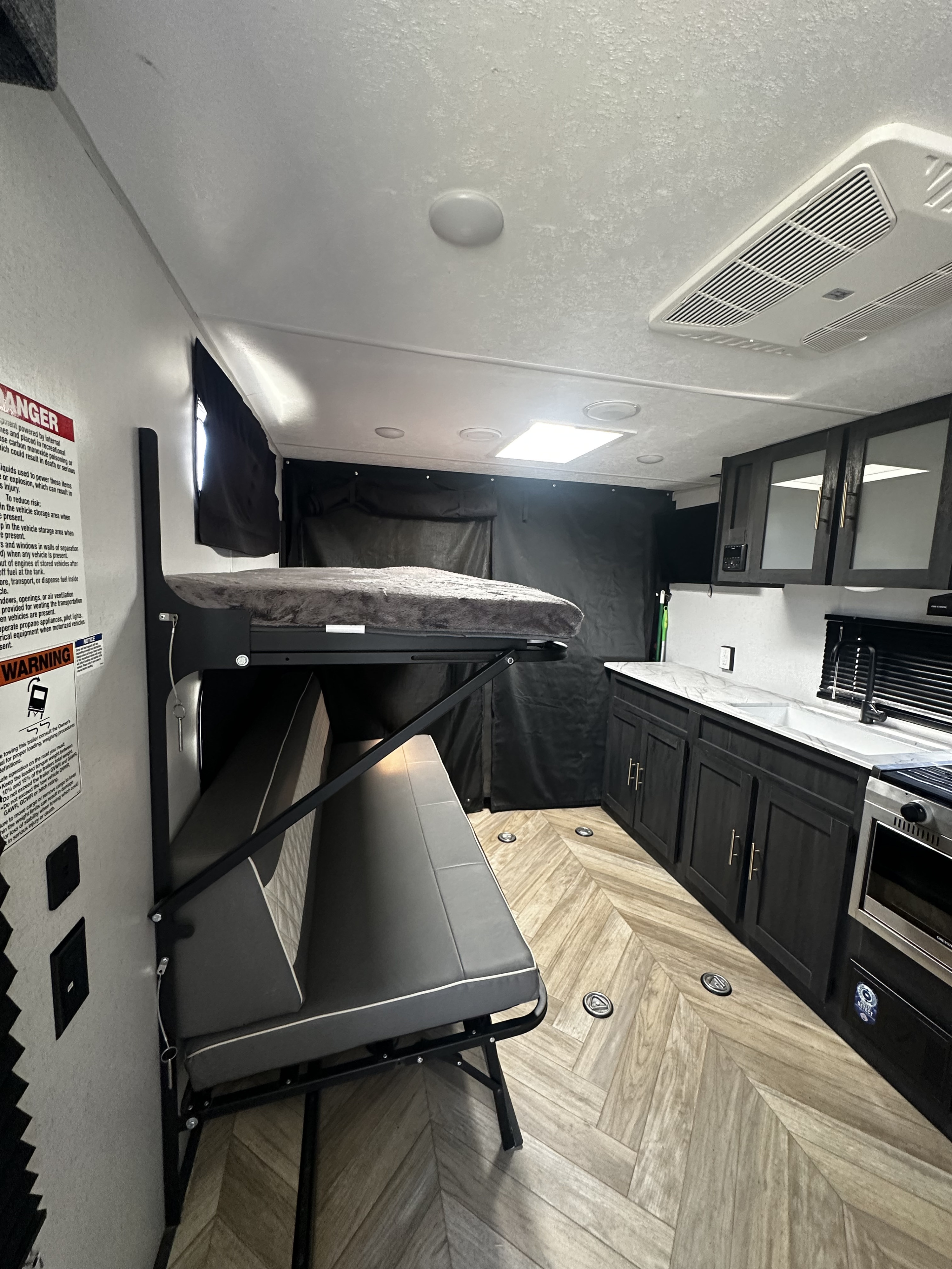 Flexible RV rental interior with bunk bed, convertible sofa, and modern kitchen.. Forest River Ozark 2022