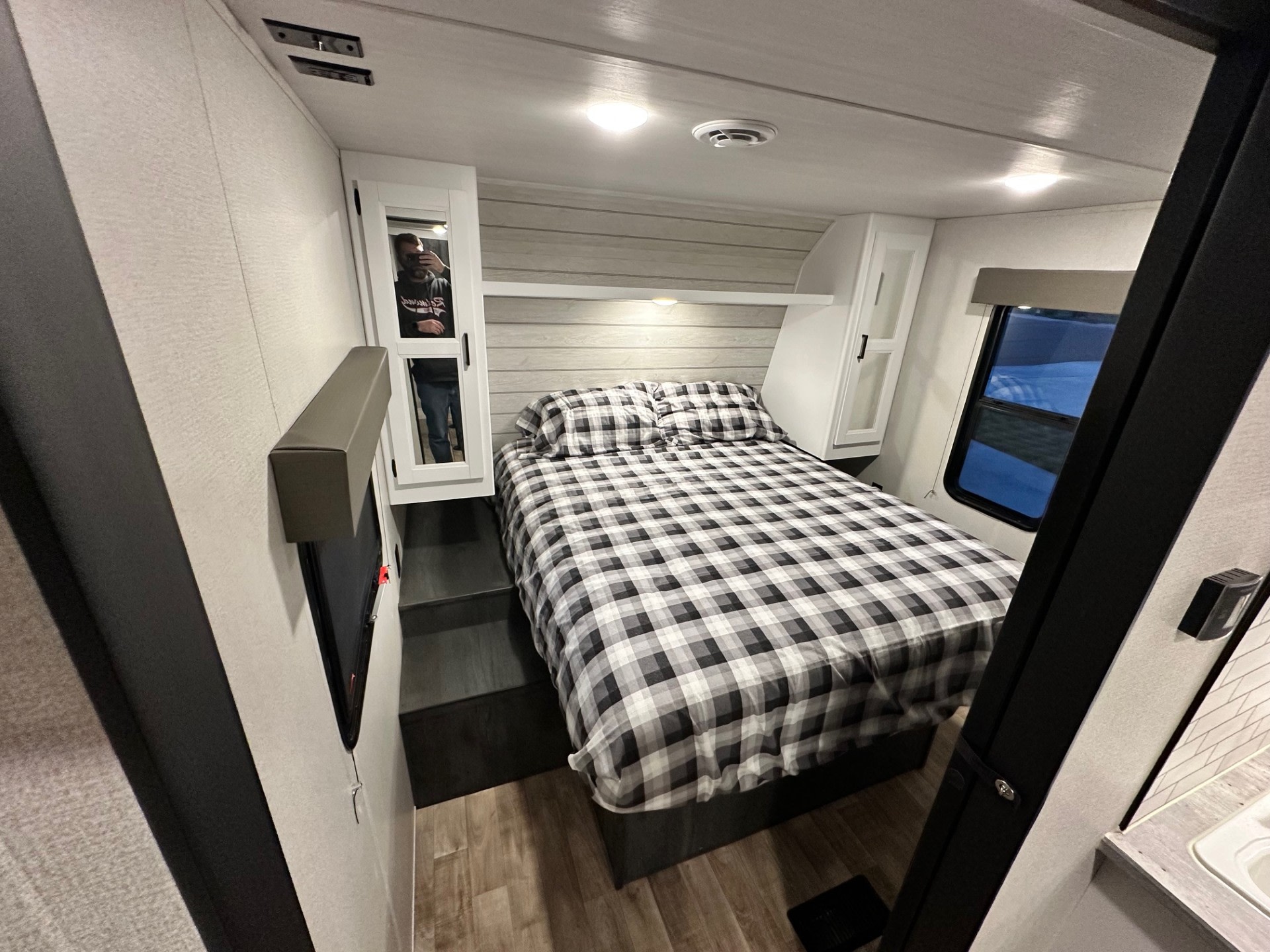 Cozy RV rental bedroom interior with a comfy plaid bed, smart storage, and a window for natural light. Perfect for travel!. Keystone RV Hideout 2022